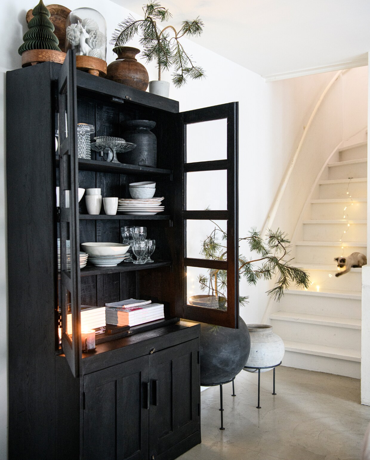 Vitrinekast Hutch, vazen en waterpotten op voet van Raw Materials. Stolp en vazen op de kast kringloop, glaswerk Dille &amp; Kamille. Servies Loods 5, Casa, Earthen By Bryck en House Doctor. Magazines vtwonen en vtverbouwen. Overig onbekend. vtwonen 13-2023 | productie Insidehomepage | fotografie Louis Lemaire