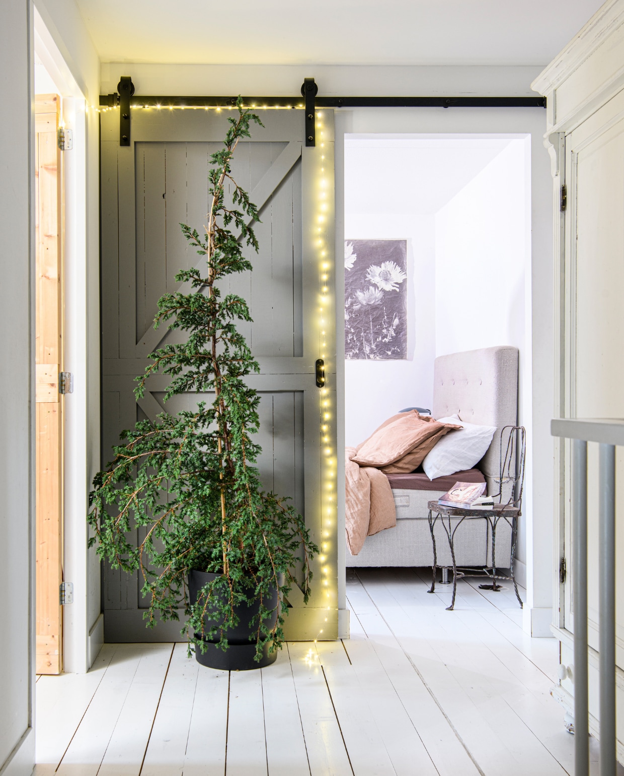 Muurverf Marrakech Walls Old Rose van Pure &amp; Original, vloerlak in Ral 9003 Signaalwit van Sikkens, schuifdeur gemaakt door aannemer. Plant Juniperus Chinensis van Jeneverbes Kweker, pot Tuincentrum Osdorp, wanddoek Old Dutch Canvas met Natuurprint van More Than Canvas. Beddengoed en kussens H&amp;M Home. Stoel Raw Materials, kast kringloop, lichtsnoer Kerstverlichting Buiten. Overig onbekend. vtwonen 13-2023 | productie Insidehomepage | fotografie Louis Lemaire