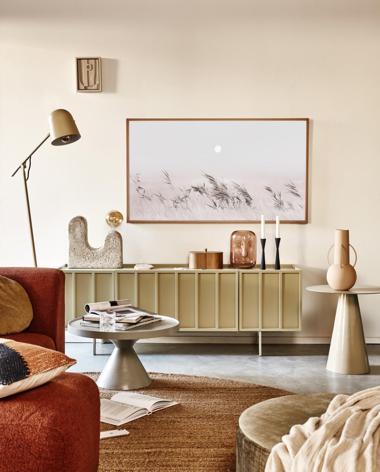 Televisie The Frame, 55 inch, teakhouten lijst The Frame, met afbeelding uit de Art Store (samsung.nl). Metalen dressoir Pebble, 159x40x55 cm (bxdxh), wilgenhouten doos, gemêleerd kussen, 60x40 cm, rond hennep vloerkleed, 250 cm (Ø), metalen bijzettafel Cream rechts (hkliving.nl). Handgemaakte schemerlamp Lampara W (lanena-home.com). Bruine vaas Long Face van Bloomingville, matzwarte kandelaars, 20 cm (h), lichtroze vaas van Pols Potten op bijzettafel, set van 3, poef Pearl XL, 80x28 cm (Øxh) (vtwonen.nl).Grijze metalen salontafel Floss, lichtgroene staande lamp Floor (zuiver.nl). Plaid, 220x200 cm (zarahome.nl). Overig privébezit. vtwonen 02-2022 | styling Esther Jostmeijer | fotografie Bart Brussee