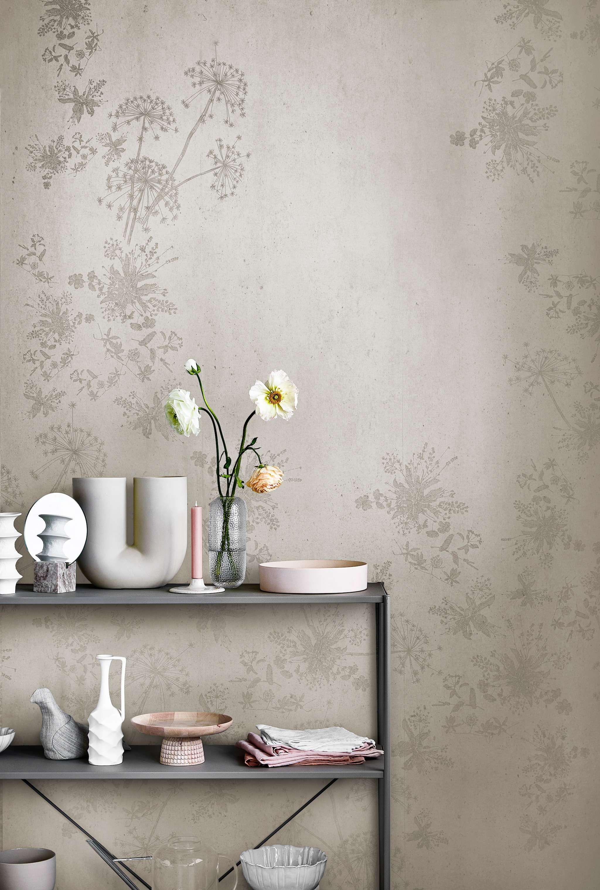 Digitaal behang Wild Flower Concrete, 6 banen van 280×50 cm, totaal (lxb) 280×300 cm. M.m.v. loods5.nl (stellingkast), loods5.nl/design (witte vazen uit set van vier, roze schaal), hm.com (spiegel in marmeren blok), kasstoor.nl (U-vormige vaas, houten etagère), letoile.store (kandelaar, roze theedoeken), bolia.com (glazen vaas, gebroken-witte schaal), homestede.nl (stoffen vogel), paviljoennoord.com (schalen met geschulpte rand, witte theedoeken), hm.com (glazen gieter). Overig privébezit. vtwonen 05-2021 | productie Tanja Saarberg | styling Danielle Verheul | fotografie Peggy Janssen