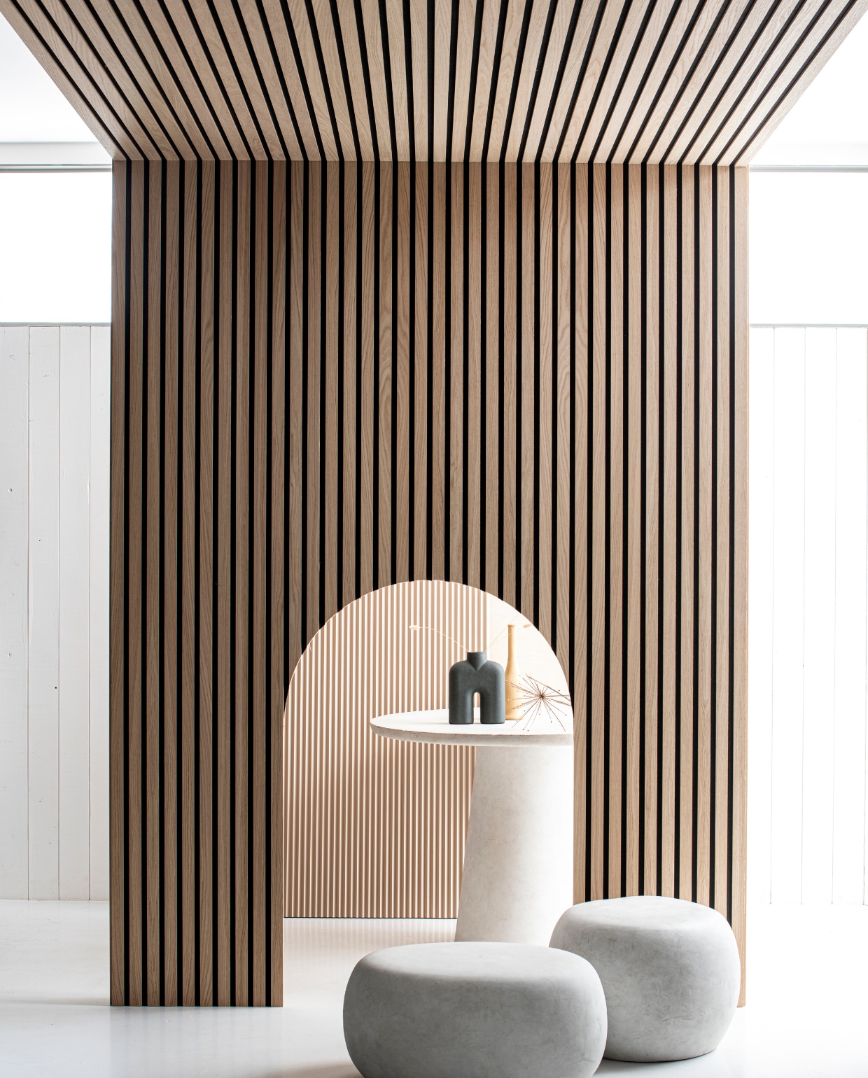 Op maat gemaakte akoestische wand- en plafondpanelen in eikenfineer, kleur/finish Nature met gerecycled vilt, 30x278 cm, (Wood-Lines). Bijzettafel Pebble betonlook wit, 31x65x49 cm (vtwonen via basiclabel.nl). Bijzettafel Pebble betonlook wit, 35x50 cm (hxØ] (vtwonen via basiclabel.nl). Eettafel Damon betonlook wit, 76x100 cm (hxØ] (WOOOD via basiclabel.nl). Vaas Cobra Tall Mini van 101 Copenhagen (Loods 5 Design). Zandkleurige vaas (privébezit). vtverbouwen vloer &amp; wand 2 2022 | productie &amp; styling Studio Marit Saladini | fotografie Louis Lemaire