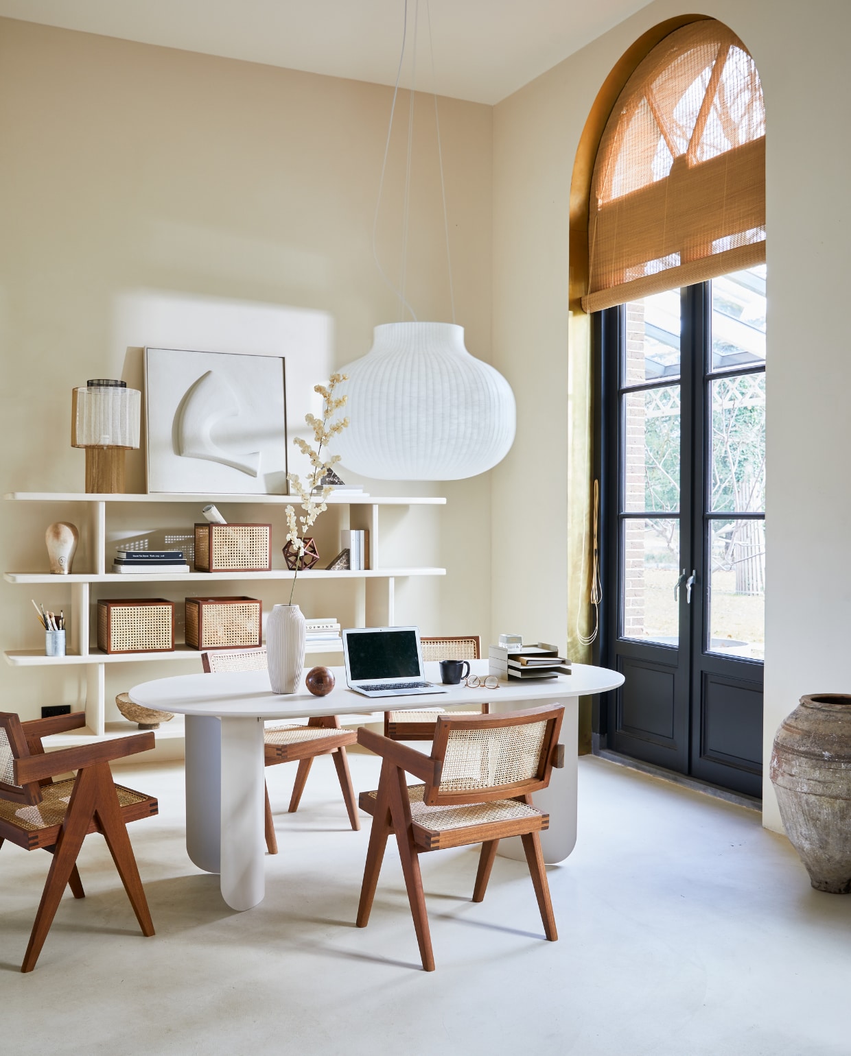 Ovale tafel Plateau in zandtint, gepoedercoat staal en mdf eikenfineer, 200x90x74 cm (bxdxh)(festamsterdam.com). Stoel van ontwerper Pierre Jeanneret (objectembassy.com). Hanglamp Strand Closed van Muuto, 80x54,8 cm (Øxh) (nordicnew.nl). Open kast op maat gemaakt (com-anders.nl). Opbergmanden rotan, 26x31x35cm (hxdxb) (hm.com). Lamp op kast (anoukb.com). Vaas (nordal.eu). Schilderij (tessaderijk.com). Marmeren boekensteunen (blomus.com). Metalen organizer, 22,8x12,7x28,3 cm (bxhxd)(fermliving.com). Overig privébezit. vtwonen 04-2021 | styling Cleo Scheulderman | fotografie Jeroen van der Spek