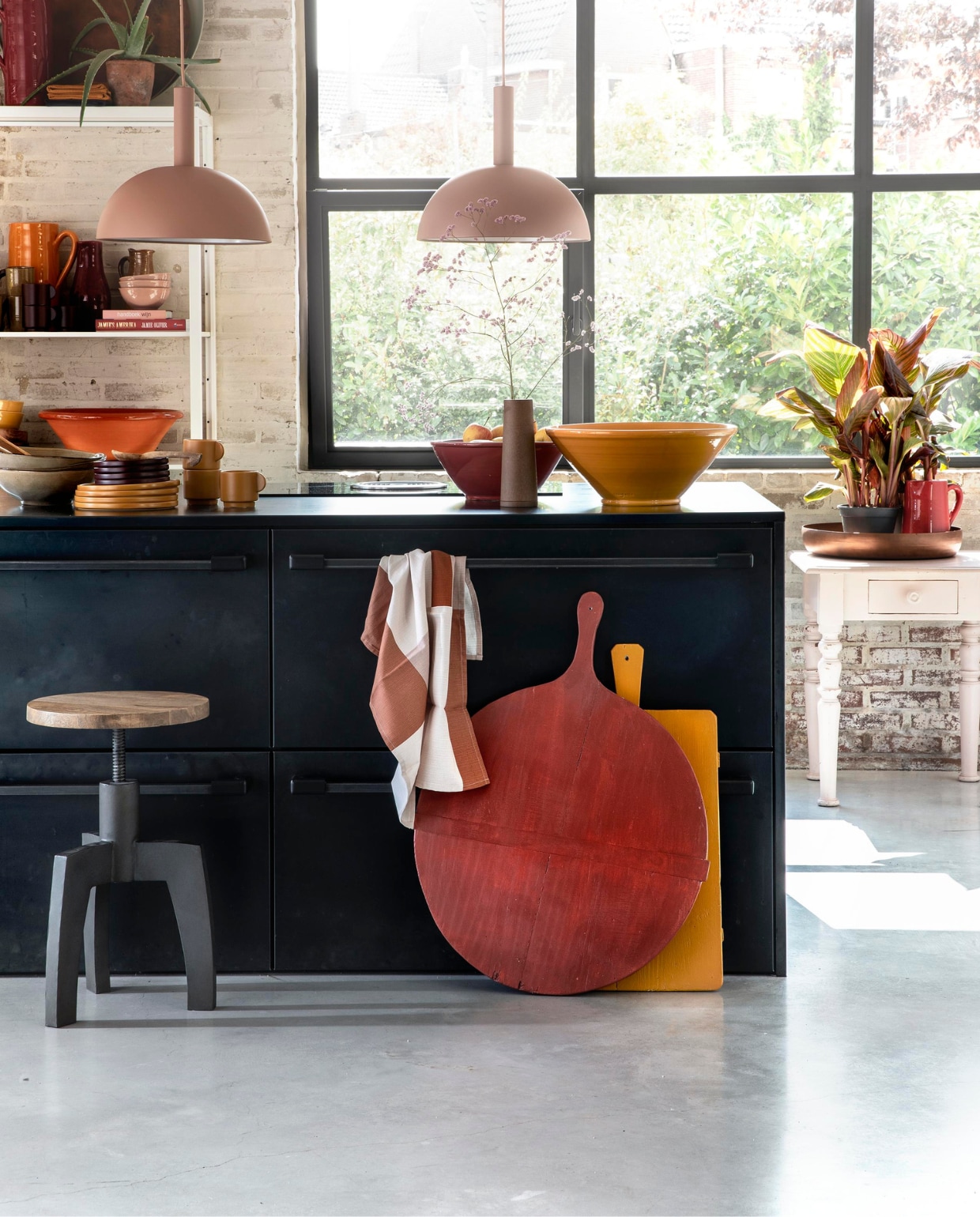 Zachtroze hanglampen Dome Shade van Ferm Living inclusief roze fitting high (vtwonen.nl). Draaikruk Space van BepureHome (Woondock). Grote oude kaasplanken (H&M Home), gelakt met Perfection zijdeglans lak in dieprood en mosterdgeel, 750 ml (Histor). Theedoek, okergele kopjes, okergele borden, donkerpaarse borden (H&M Home). Okergele schaal, donkerrode schaal (In-Petto). Beige schalen (Intratuin). Bovenop de kast: grote donkerrode kan (In-Petto), theedoeken in okergeel en donkerpaars (H&M Home), koperkleurige schaal van BePureHome, zachtgroene schaal (Woondock). Midden in de kast: zachtroze schaaltjes, okergele kan (In-Petto). Donkerpaarse kopjes (H&M Home). Donkerrode karaf Nikki, lichtbruine karaf (Intratuin). Beige kan (Intratuin). Onder in de kast: terracotta schaal, okergele diepe borden (In-petto). Zachtroze tafeltje (Combitex). Koperkleurige schaal Big Waitress van BePureHome (Woondock). Donkerrode kleine kan(In-Petto). Kamerplanten Canna Hybride (Intratuin). De keuken is een eigen ontwerp van de bewoners, binnenwerk van hout, blad en kasten afgewerkt met blauw staal. Overig privébezit. vtwonen 11-2018 | styling Moniek Visser | fotografie Peggy Janssen