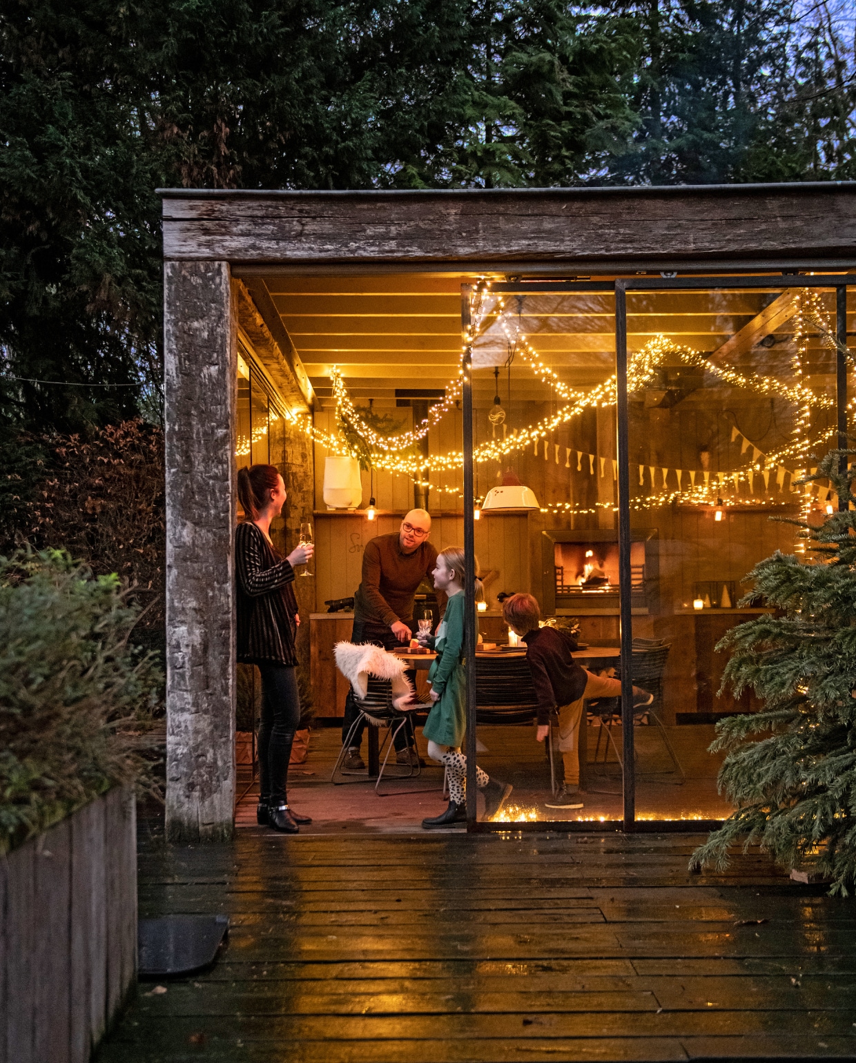 Naast de garage is een buitenkeuken gebouwd, met een constructie van oude meerpalen en stalen ramen. De binnenkant is afgewerkt met barnwood, de haard en houtopslag kregen een stalen lijst. Het werkblad is van beton. Barbecue Green Egg. Lichtjessnoer en lampen van Snoerboer, slinger van Enjoy Ooi. vtwonen 12-2019 | styling Babs Dols | fotografie Louis Lemaire | productie insidehomepage
