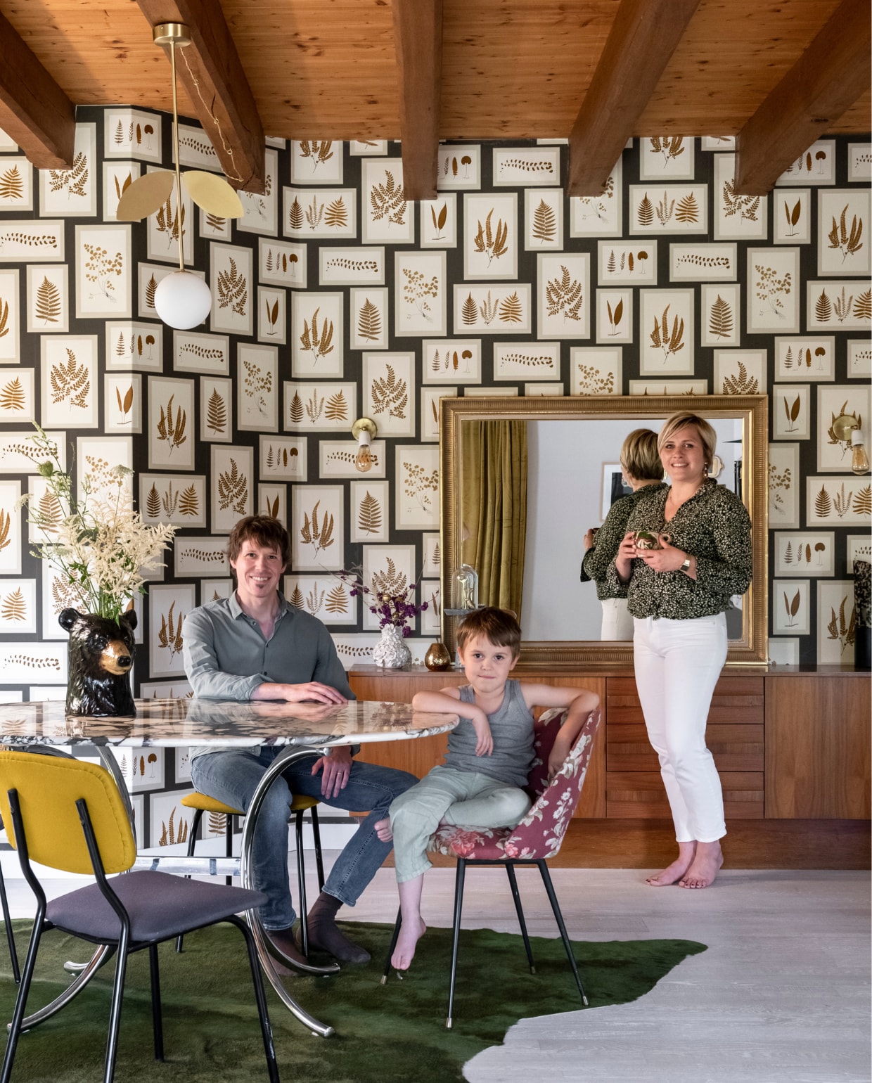 Mélanie, Guillaume en zoon Léopold aan de eetkamertafel in hun Franse villa. Behang Sanderson, vloerkleed Pols Potten, stoel bloemenstof Héritage Studio, andere stoelen vintage met stof van Pierre Frey, eettafel Mwell Studio en Héritage Studio, hanglamp Atelier Areti, beervaas souvenir uit Finland, vazen op dressoir H&amp;MHome. Overig vintage. vtwonen binnenkijken special 121-2021 | productie A&amp;J | fotografie Julien Fernandez