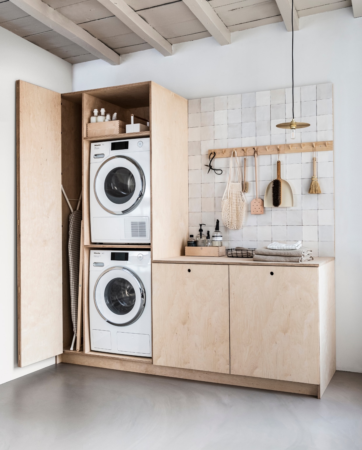 Strijkplank Ruter, strijkplankhoes Lagt, witte handdoeken Saliken (ikea.nl). Houten wasrek, berkenhouten vierkante opbergbox, witte toolbox large, berkenhouten rek met 7 haken, berkenhouten rek met 4 haken, schaar, houten afwasborstel, stoffer en blik, berkenhouten opbergbox smal, knitted handdoeken (irishantverk.se). Wasmachine WWR760 WPS PWash2.0 &amp; TDos XL &amp; Wifi, met automatisch doseringssysteem en quick power wash en ook WiFiconnect, droger TWR860 WP Eco&amp;Steam Wifi&amp;XL met WiFiconnect (miele.nl). Wasmiddel (hema.nl), hanglamp FramaCircle Shade, leren vliegenmepper(bymolle.com). Nettas natural, zwart draadmandje (thefinestore.com). Lichtgrijze wasmanden Laundry L van Hay, tegels Craft Egg van vtwonen, white mat 12,5x12,5 cm per m2 (vtwonen.nl). Theedoek met ruit (hm.com). Overig privébezit. vtwonen 04-2019 | productie &amp; styling Kim van Rossenberg | uitvoering Richard van Meerveld fotografie Sjoerd Eickmans