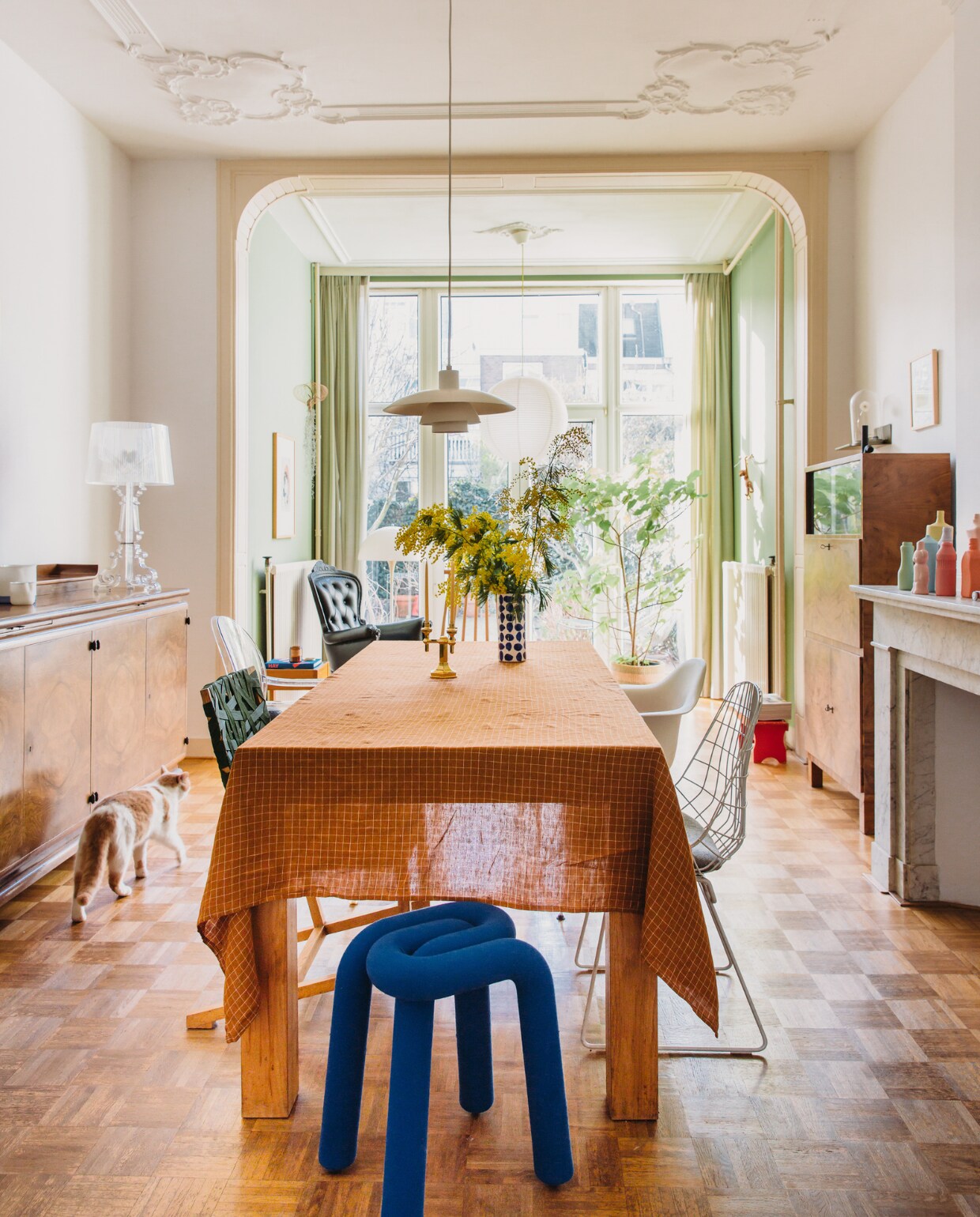 Tafelkleed Merci. Stoelen Vitra, Richard Hutten, Philippe Starck en Pastoe, kruk Bold Stool van Moustache. Kandelaar Michela Castagnaro. Vintage hanglamp Louis Poulsen. Jaren 20-dressoir en vitrinekast familiestukken. Tafellamp Bourgie van Kartell. Keramiek op dressoir Piet Stockmans. Vazen op schouw Foekje Fleur. Kunstwerk op vitrinekast Dandlelight van Studio Drift. Tekening aan de muur Marije Tolman, stoel Smoke Chair van Maarten Baas voor Moooi, plant Studio Carolijn Slottje, rijst-papieren lamp Hay. Aap Kay Bojesen. Muurverf serre Breakfast Room Green van Farrow &amp; Ball. Overig onbekend. vtwonen special binnenkijken 121-2023 | styling StyleStek | fotografie Eva Bloem