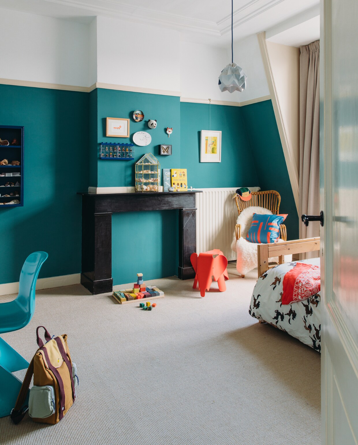 Muurverf Canton van Little Greene. Vintage bureaustoel Kangaroo van Ernst Moeckl. Rugtas Sticky Lemon, blokkendoos Raduga Grëz en pet New Kids in the House via Stokstaart. Klein bord souvenir, groot bord Gurli Feilberg, IJsje Odette Muijsers, blauwe vitrine Lego, schelpenverzameling in vintage vitrinekast Sprinkelhop. Ingelijste tekening en prent Marije Tolman. Rode olifant Eames van Vitra. Rotan stoel Rohé Noordwolde, kussen Jantien Baas. Dekbed-overtrek Mini Rodini. Lamp Studio Snowpuppe. Overig onbekend. vtwonen special binnenkijken 121-2023 | styling StyleStek | fotografie Eva Bloem