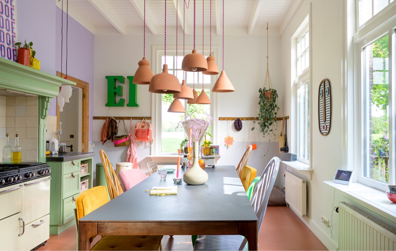 Muurverf WO.20.60 en verf kast in Mild Jade van Flexa. Verf plafond Ral 9010 van Sikkens. Vloer beton ciré in 10-26 Rose Red van Stone Age. Keuken op maat gemaakt door vorige bewoner, tegels Azulejos Blanco Cristal van Designtegels, fornuis Stoves van Richmond. Eettafel Sav &amp; Økse, eetkamerstoelen Fatboy, Vitra, HKliving, Zuiver en kringloopwinkel. Terracotta hanglampen Household Hardware. Vaas en kandelaars Urban Nature Culture. Letters Wilma@home. Prullenbakken Brabantia. Overig onbekend. vtwonen special binnenkijken 121-2023 | fotografie Trui Heinhuis