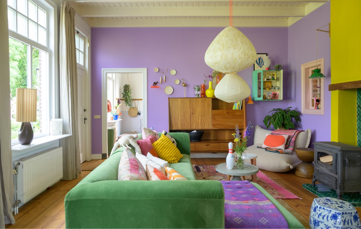 Muurverf paars WO.20.60 van Flexa. Muurverf geel GO.60.60 en verf plafond Ral 9010 van Sikkens. Originele eikenhouten vloer opgeschuurd en behandeld met Osmo Hardwaxolie. Bank HKliving, kussens Ikea, Fatboy, Urban Nature Culture, Van Verre en kringloopwinkel, plaid Van Verre. Vintage kast Marktplaats. Wandkast Van Dijk & Ko. Zitzak Fatboy. Bijzettafels Loods 5, Kleine Gelukjes en Urban Nature Culture. Kruk TipToe, kegel Vintage Friends, vaas Urban Nature Culture. Hanglampen HKliving. Vloerkleden Evenaar en Wanderwood. Kachel Efel. Overig onbekend. vtwonen special binnenkijken 121-2023 | fotografie trui heinhuis