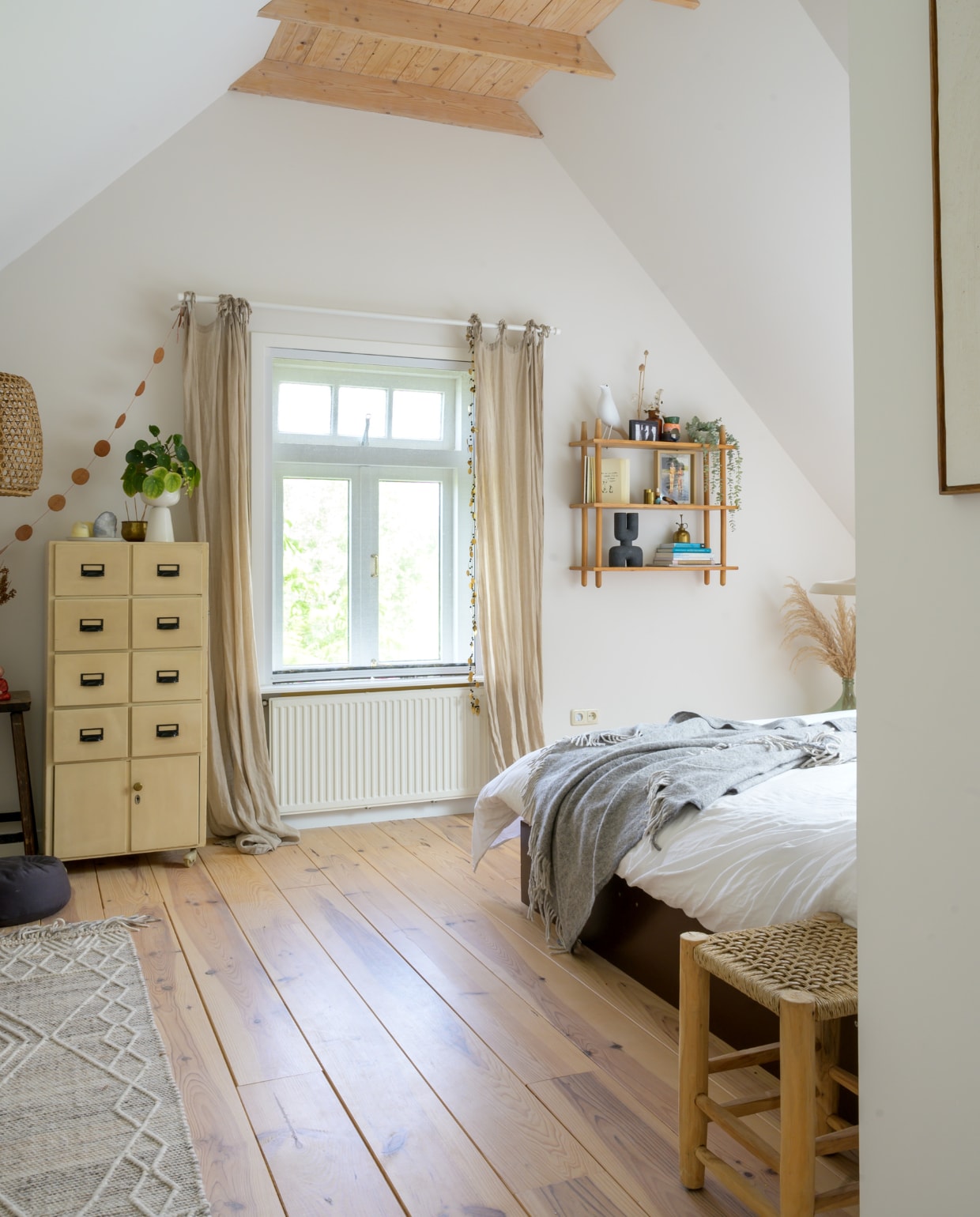 Originele houten vloer behandeld met Osmo White Wash Olie. Bed zelfgemaakt. Plaid en gordijnen Ikea. Vintage archiefkast Brocantiek Memories. Kruk Ibiza Outdoor. Vloerkleed Kwantum. Opbergrek Marktplaats, vogel Eames House Bird van Vitra, diverse objecten Urban Nature Culture en kringloopwinkel. Overig onbekend. vtwonen special binnenkijken 121-2023 | fotografie Trui Heinhuis