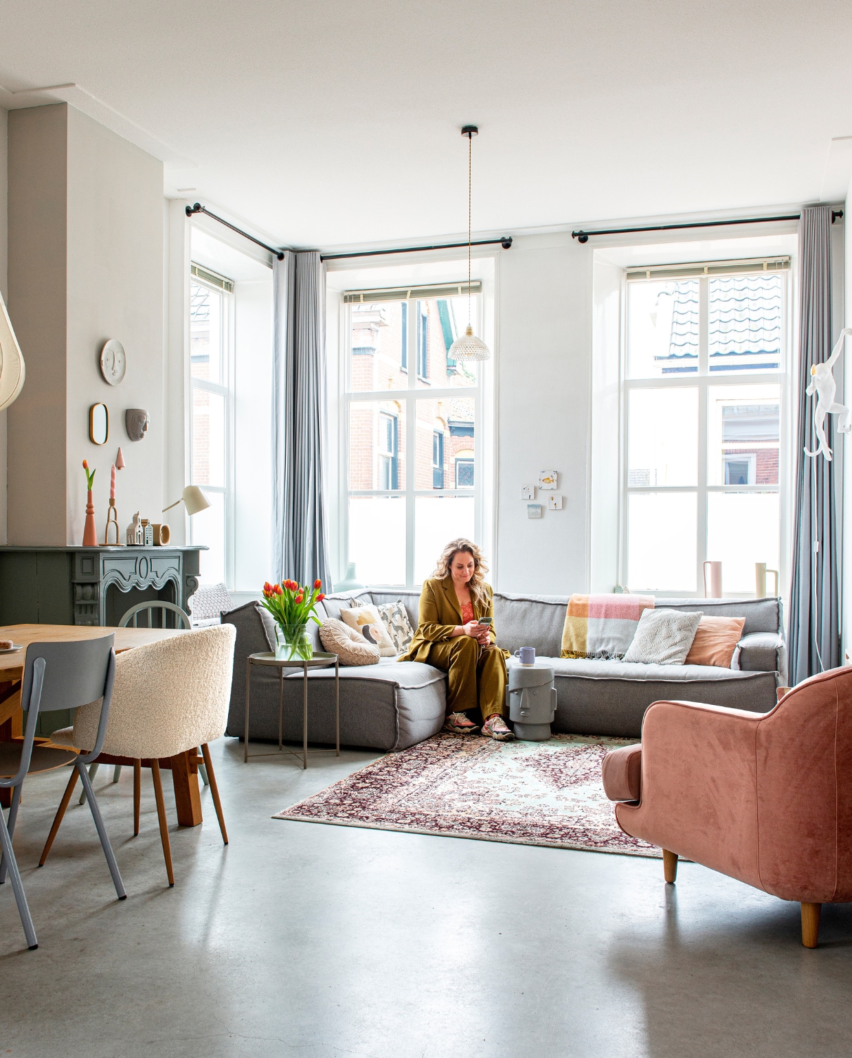 Bank Trendhopper. Fauteuil Made. Kruk Donny van Coco Maison. Tafel, beige stoel, bijzetter en gordijnroedes Ikea. Grijze stoel en tafellamp Zuiver, wandlamp Monkey van Seletti, vintage hanglampje @tweedesans, hanglamp Bolia. Vachtstoel Søstrene Grene, kinderstoel rommelmarkt. Vloerkleed vintage. Kussens: roze Loods 5, grafisch, alpaca H&amp;M Home. Plaid Fatboy. Tegels Storytiles. Vazen vensterbank (zelf geverfd) Kwantum. Gordijnen Hema. Jaloezieën Veneta. Kaars Plek conceptstore. Roze vaas en kandelaar Karwei, kerkje en mok Xenos, huisje Hema. Wandbord Kwantum. Keramieken kerstboom Marleen Out. Wandvaas gezicht Presenttime. Pak Ydence, sneakers Zara. Verf op schouw Early Dew van Flexa, op schoorsteenmantel grijze grondverf. Betonvloer. Overig onbekend. vtwonen 08-2022 | productie De Binnenkijkers | styling Jeske Weel | fotografie Caroline Coehorst