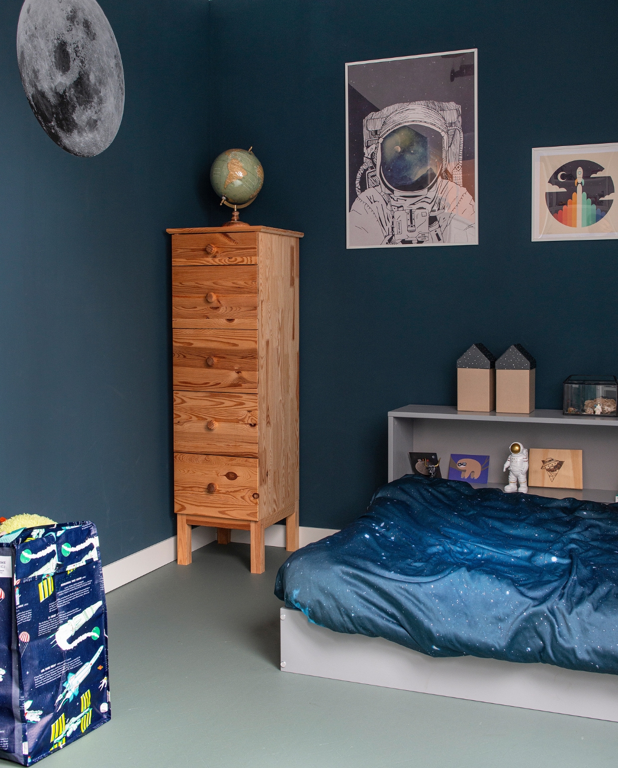 Bed Woood. Kast, lijsten en cirkel Maan Ikea. Wereldbol Action. Tas Rex London. Huisjes H&amp;M Home. Poster astronaut Desenio, poster raket Junique. Muurverf Nachtblauw van Flexa. Vloer Bella Origami Groen van Novilon. Overig onbekend vtwonen 08-2022 | productie De Binnenkijkers | styling Jeske Weel | fotografie Caroline Coehorst