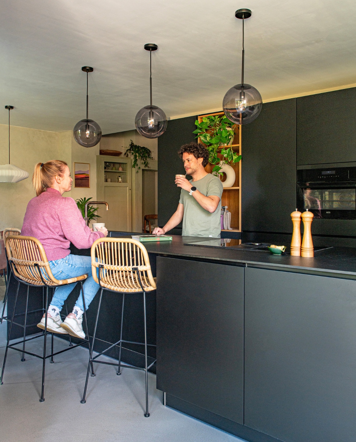 Keuken Kvik, barkrukken Leen Bakker, bollampen Bolia, witte hanglamp Kwantum, peper-en-zoutstel Dille &amp; Kamille, vaas in kast H&amp;M Home, kalkverf Mushroom van Lab Paint, topvloer woonbeton van Coatingvloer.nl. Overig onbekend. vtwonen 01-2024 | productie De Binnenkijkers | styling Jeske Weel | fotografie Caroline Coehorst