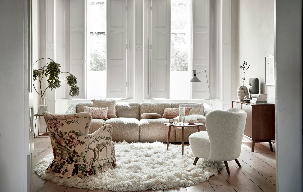 Beige 4-zitsbank Cooper Luno, 300x97x72 cm (bxdxh), beige kussen met streep, juten kussen, kussen Zoe van Apelt van gerecyclede petflessen, walnoothouten dressoir Darcy, grijze keramieken vaas Tribal van 101 Copenhagen, walnoothouten bijzettafel, waterkaraf, drinkglazen, bijzettafel linksachter, vaas links (loods5.nl). Schaal, witte keramieken vaas Bubble (sissy-boy.com). Kleine vaas, schapenvacht (kwantum.nl). Schilderij Follow Rivers, 40x50 cm (tinystories.nl). Hoogpolig wit vloerkleed Fluffy, 250 cm (Ø), wol en katoen, crèmekleurig kussen met geborduurd patroon, bruin rond rib kussen (hkliving.com). Metalen vloerlamp Hoodies van vtwonen, fauteuil Cosy van By Fonq, hout en kunststof, (vtwonen.nl/shop). Jaren 50 vintage fauteuil van Theo Ruth voor Artifort in Aviary-dessin (neeflouis.nl). Overig privébezit. vtwonen 12-2023 | styling Kim Timmerman | fotografie Peggy janssen