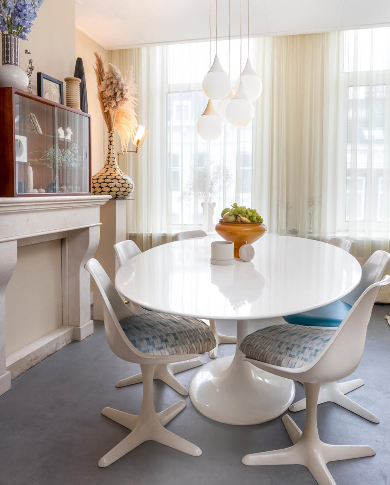 Muurverf Gentle Cotton van Bierens. Schouw tweedehands via Marktplaats. Kastje vintage, element van modulaire jaren 60-wandkast Poul Cadovius. Hanglamp kringloop. Vintage Tulip-tafel Eero Saarinen, vintage stoelen Maurice Burke voor Arkana. Fruitschaal glazen kap van olielamp uit de jaren 70 met een vintage tinnen schaaltje erop. Gordijnen tweedehands via Marktplaats. Overig kringloop. vtwonen 08-2022 | styling Kesslee Kasius | fotografie Henny van Belkom