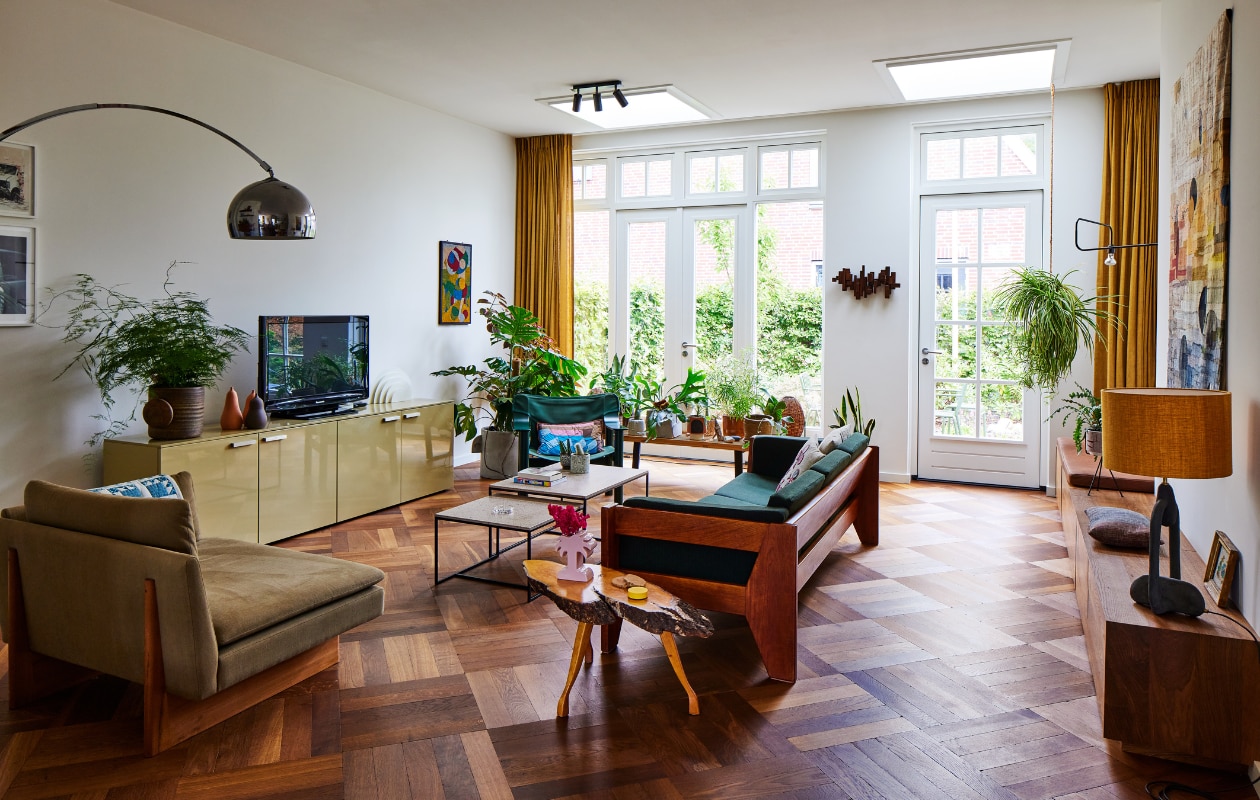 Loveseat Sofa, muurlamp, schemerlamp, wandkleed en muurbank X+L. Groene bank, peren, bijzettafel boom, klein schilderij vintage. Kussens zelfgemaakt, palmboomvaas Stüssy, salontafels Schriever Interieurbouw, dressoir Cappellini, vintage plantenpot Mobach Keramiek, witte lamp Raak, vilten kunstwerk Marktplaats, groene fauteuil Hay, kussen A.p.c., houten bank Nelson Platform Bench. Diverse potten Wildernis, vintage en Serax. Wandsculptuur Ming Stylemeister, spotjes Sofisticato van Koen Van Guijze van Serax. Overig onbekend. vtwonen 11-2023 | styling Mariella Kallenberg | fotografie René Mesman