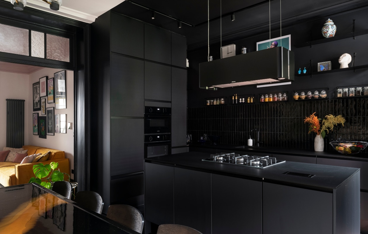 Keukenkasten Èggo, werkblad Bertrand, wandtegels Vernici van Sartoria, afzuigkap Airforce. Klok en fruitmand Kartell. Ingelijste foto Nicolas Guérin van YellowKorner. Zeeppomp H&amp;M Home, vaas Hema. Eettafel zelfgemaakt, stoelen Kave Home. Overig onbekend. vtwonen 121-2023 | styling Amélie Jacob | fotografie Jonah Samyn