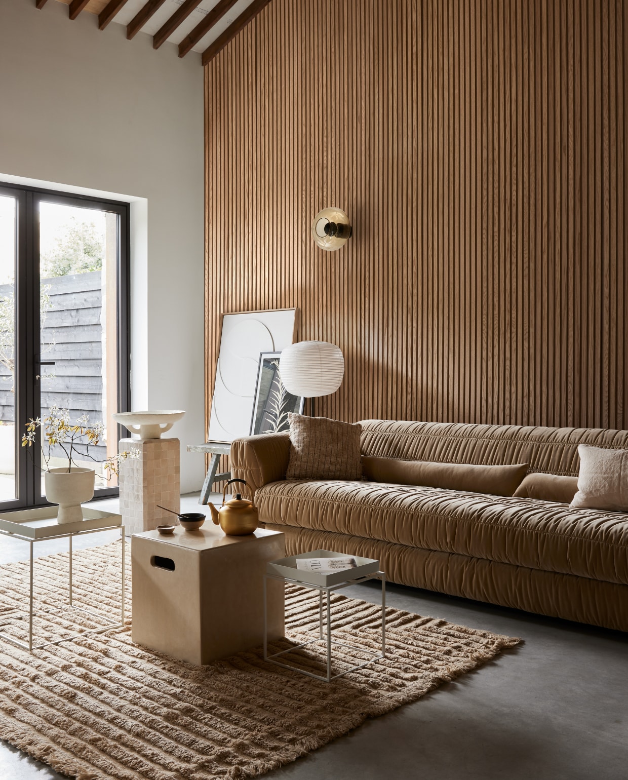 Akoestische wandpanelen van eikenhout en beige vilt, 60x240 cm (bxh) (noakk.nl). Bank Club Couch in Royal Velvet Cream, 108x74x72 cm (bxdxh) (hkliving.nl). Wollen vloerkleed Crease van Ferm Living, 250x160 cm (bxh), katoenen kussen links Febbie van Bloomingville, 45x45 cm, papieren schaal Earth van Serax (vtwonen.nl/shop). Linnen kussen rechts, 50x30 cm (sukha.nl). Rijstpapieren lampenkap Common, 44x39 cm (Øxh), lichtgrijze stalen salontafel Tray, 30x30x34 cm (lxbxh), witte stalen salontafel Tray, 60x40x39 cm (lxbxh) (hay.nl). Tadelakt tafel Cube, 40x40x40 cm (bxdxh), tafel met zelliges, 30x30x60 cm (bxdxh), tadelakt vaas, theepot, kom, walnoothouten schaal (householdhardware.nl). Poster Solidago Gigantea ll van Printedplant, 50x70 cm (pstrstudio.com). Reliëf kunstwerk, 83x103 cm (bxh) (hkliving.nl). Overig privébezit. vtwonen 08-2023 | styling Fietje Bruijn | fotografie Alexander van Berge