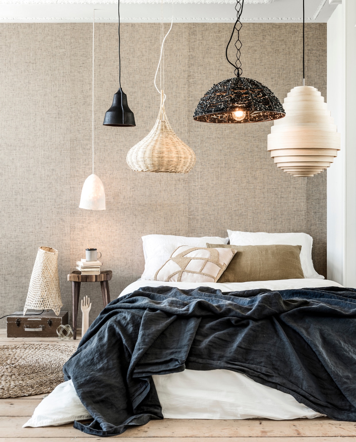 Op de koffer organische rieten tafellamp maat L (HK Living). Boven de kruk Felted Lamp Long van wol, bamboe hanglamp Union, rechts hanglamp AY Illuminate Urchin Tall, hoogte 55 cm, zwarte linnen sprei, wit linnen dekbedovertrek, bruine kussenhoes (Couleur Locale). Zwarte leren hanglamp Art Lloyd (Puik). Zwarte hanglamp van kralen Ehsan Distressed, roze kussen met kralen Hasani Beaded Cushion, mok Earth Mug Graphite (Dassie Artisan). Behang naturel 322610, 5,5x0,9 meter (Eijfinger). Houten hand (Hay). Kruk Pads van walnoothout (De Machinekamer). Jute karpet Round Natural (By-Boo). Overig privébezit. vtwonen 10-2018 | styling Marlies Does | fotografie Sjoerd Eickmans