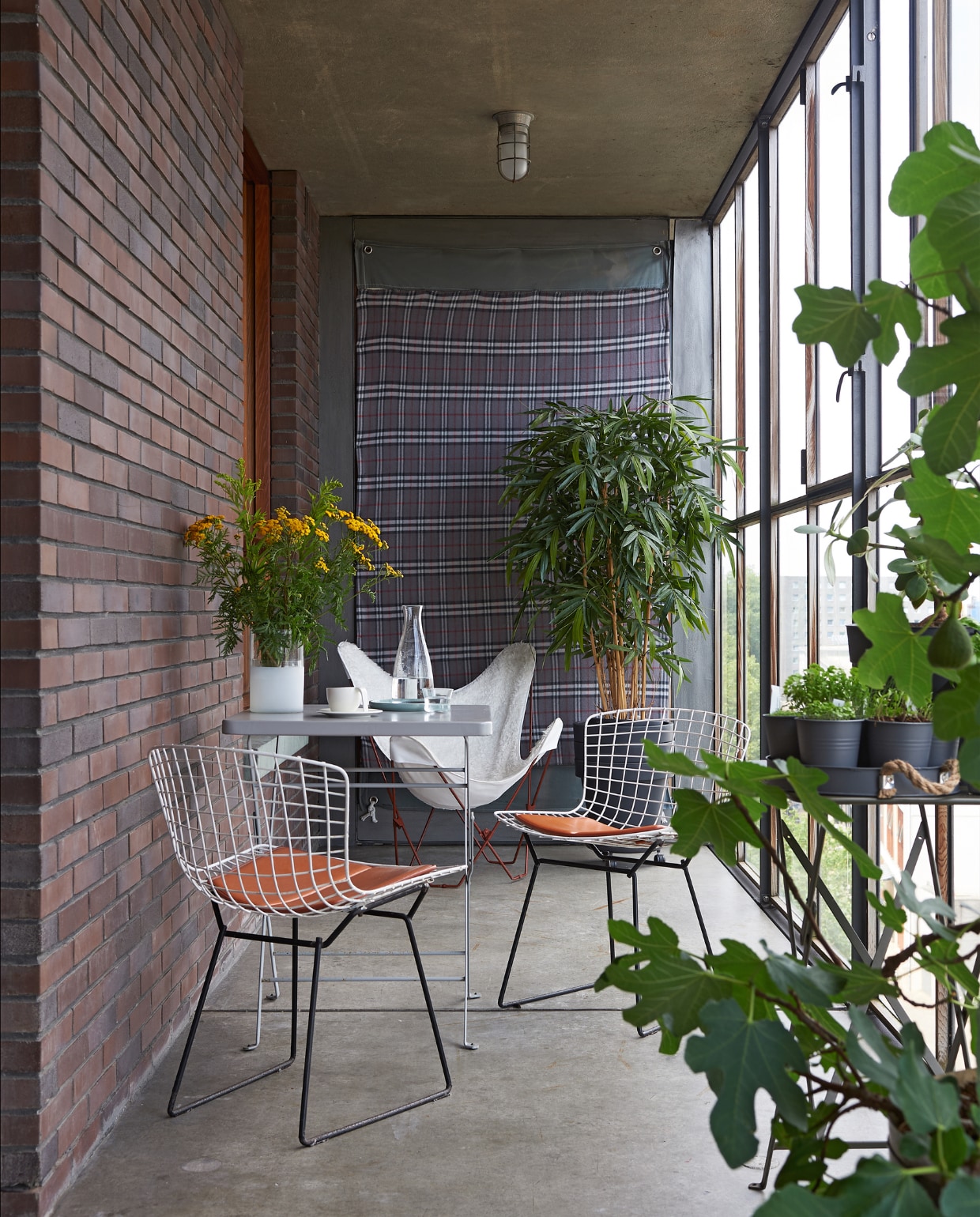 Balkon met uitzicht op het IJ. Side chairs van Harry Bertoia (Knoll), vlinderstoel met witte vacht, tafeltjes Habitat. Aan de muur een plaid van Blokker vtwonen special binnenkijken 03-2020 | styling Rob Jansen | fotografie Dennis Brandsma