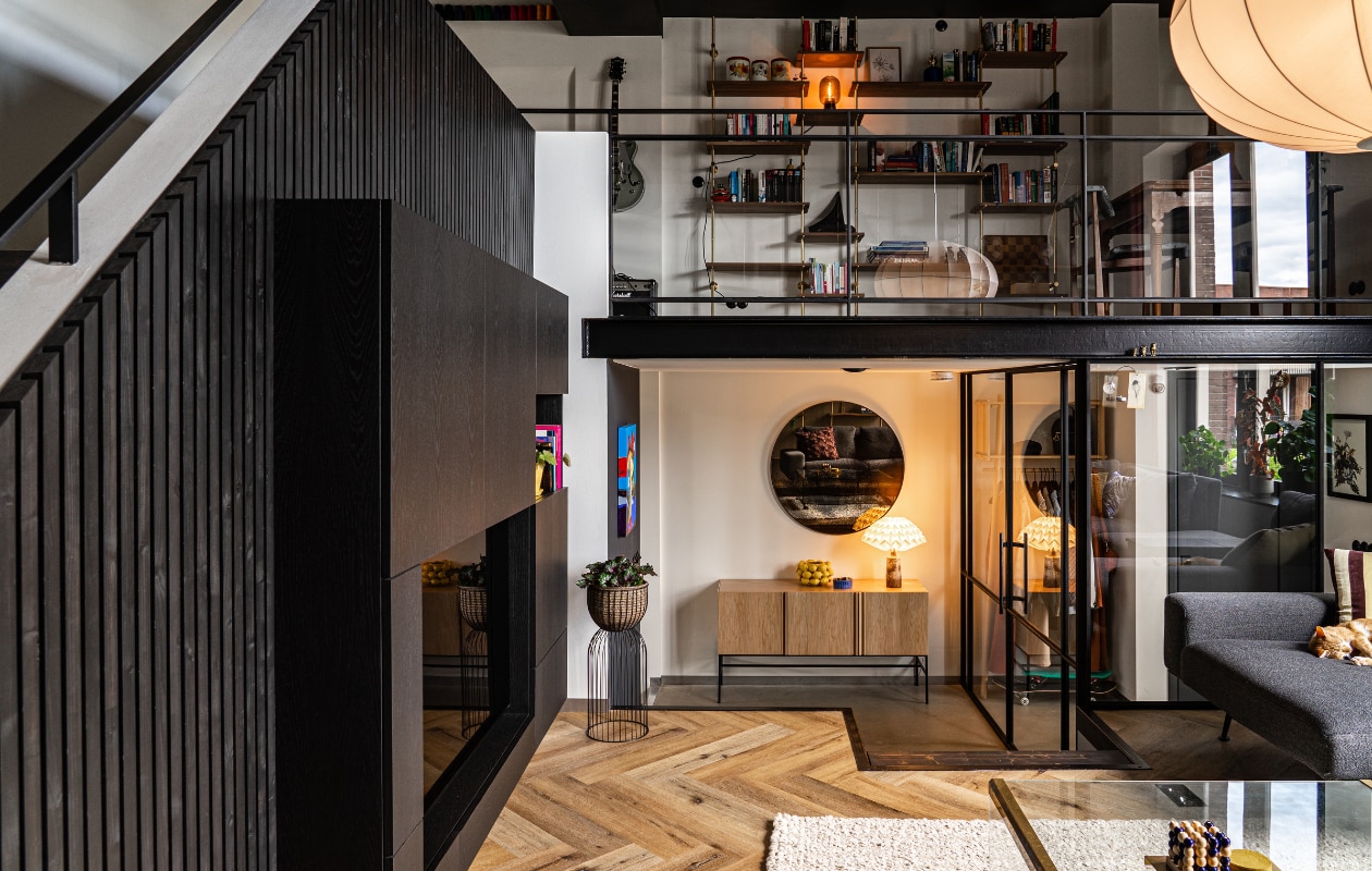 Muurverf Drift van Pure &amp; Original. Kasten eigen ontwerp van Kundertje (talenth.nl). Bank Passe Partout, bordeauxrood kussen HK Living, okergeel kussen Be Pure Home, lamp Moooi, salontafel vintage, vloerkleed de Bijenkorf. Op tafel: 4 Op ’n Rij Hema, vilten onderzetters Hay, messing tray Ferm Living. In de kast: messing vaasjes Broste Copenhagen, bloempot Iittala, olielamp Karlskrona Lampfabrik, kandelaars onbekend, fotolijstjes Moebe, Kokeshi Doll van Lucie Kaas, bureaulamp Cobra van Gubi, glazen object Swedish Ninja, organische grijze vaas HK Living, lila vaas Madam Stoltz. vtwonen 01-2022 | styling Kundertje Hamstra, Iris Floor | fotografie Iris Floor