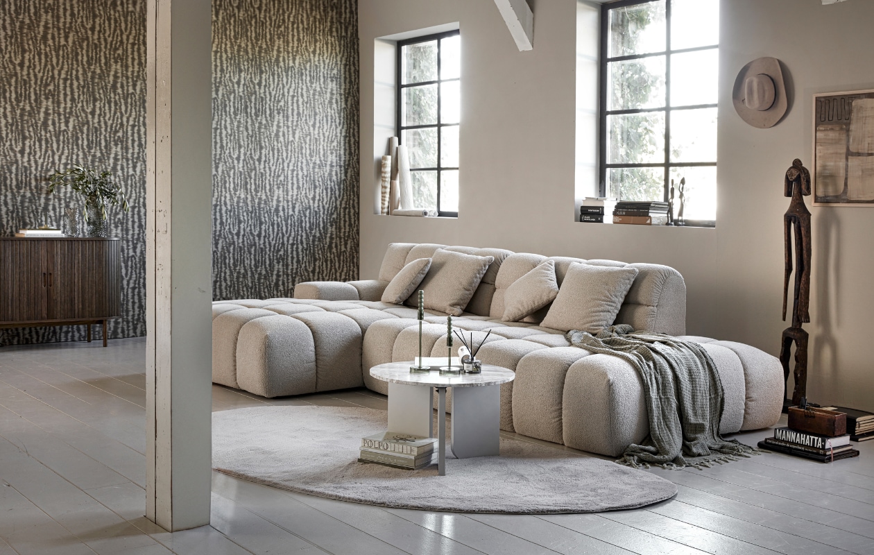 Loungebank Trentino, zelf samen te stellen, zoals afgebeeld 258x192x80 cm (bxdxh) (zitmaxx.nl). Vliesbehang Emerald Wild Ikat in 333443 van Eijffinger, 0,52x10 m (bxh) (eijffinger.com). Eikenfineer dressoir Lyngvig met 2 roldeuren, 120x40x80 cm (bxdxh), katoenen plaid Karve (jysk.nl). Geurstokjes, eikenhouten lijst 30x40 cm (hm.com). Boeken, houten tribalfiguren, groot tribalbeeld (rataplan.nl). Glazen vazen Grove, 12x22 cm (Øxh) en 18x32 cm (Øxh), polyester vloerkleed Wallace, marmerlook mdf bijzettafel Brez, glazen kandelaars Avie (kwantum.nl). Groene kaarsen (hema.nl). Kunstwerk zelfgemaakt. Overig privébezit. vtwonen 01-2024 | styling Marit Saladini | fotografie Peggy Janssen