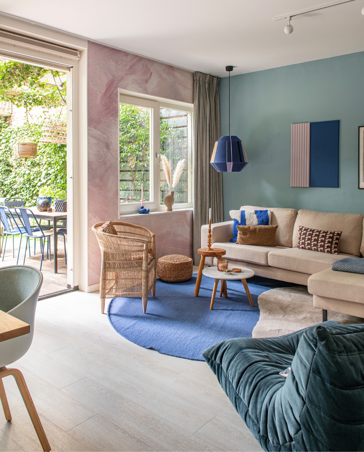 Fauteuil Togo van Ligne Roset via Fritz Vintage, blauw vloerkleed Trendcarpet, hoogpolig vloerkleed Karwei. Bijzettafels Zuiver en Zara Home. Stoel Mala Africa, hanglamp Hay, bank groothandel. Kussens HKliving, H&amp;M Home en Zara Home. Kunstwerk zelfgemaakt met Orac Decor en doek Xenos. Overig onbekend. vtwonen 01-2024 | fotografie Caroline Coehorst