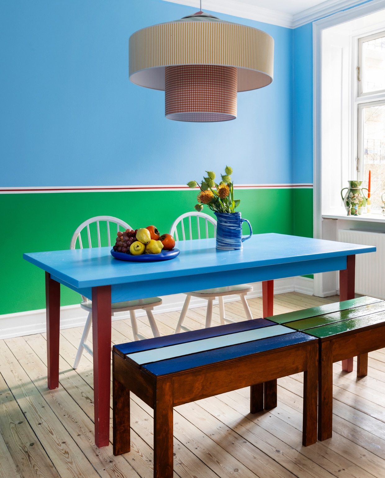 Eettafel erfstuk van Jacobs moeder, stoelen gevonden op straat, houten bank zelfgemaakt door Emma’s zus. Fruitschaal Kiosk48th, melkkan op tafel en kandelaren in vensterbank Hay. Hanglamp Hula Hoop van Gropius Lamps. Vaas rommelmarkt, vogelbeeldjes cadeau gekregen. vtwonen special binnenkijken 121-2023 | productie Living Inside | styling Rikke Graff Juel | fotografie Christina Kayser Onsgaard