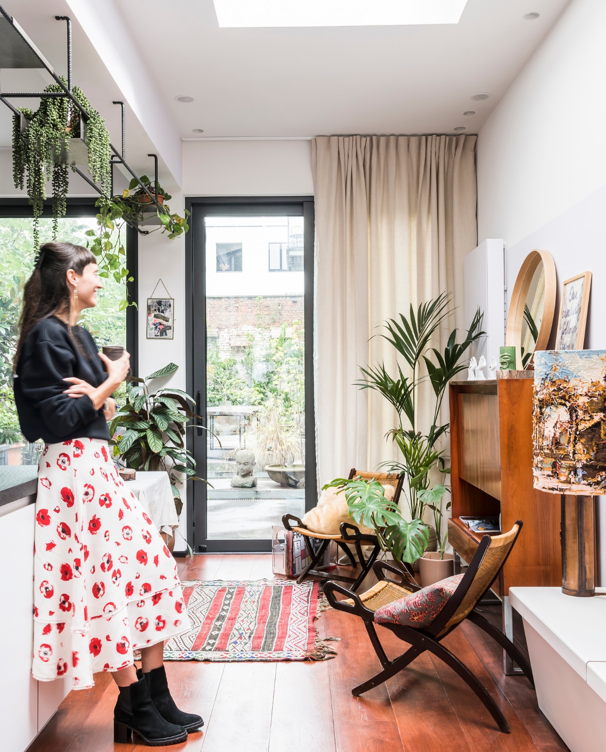 Vanuit de keuken kijkt Caroline uit op haar stadstuin waar kweeperen, appels en kruisbessen groeien. Gordijnen Moodz Designculture. Vloerkleed The Recollection, stoelen en vintage kast Cornette de Saint Cyr. Ronde spiegel Hay. Lamp met gebreide lampenkap Goldwood By Boris. Het hangrek is een eigen ontwerp, uitgevoerd door Sunaert (sunaert.com). vtwonen 10-2020 | styling Caroline De Cuyper | fotografie Jonah Samyn