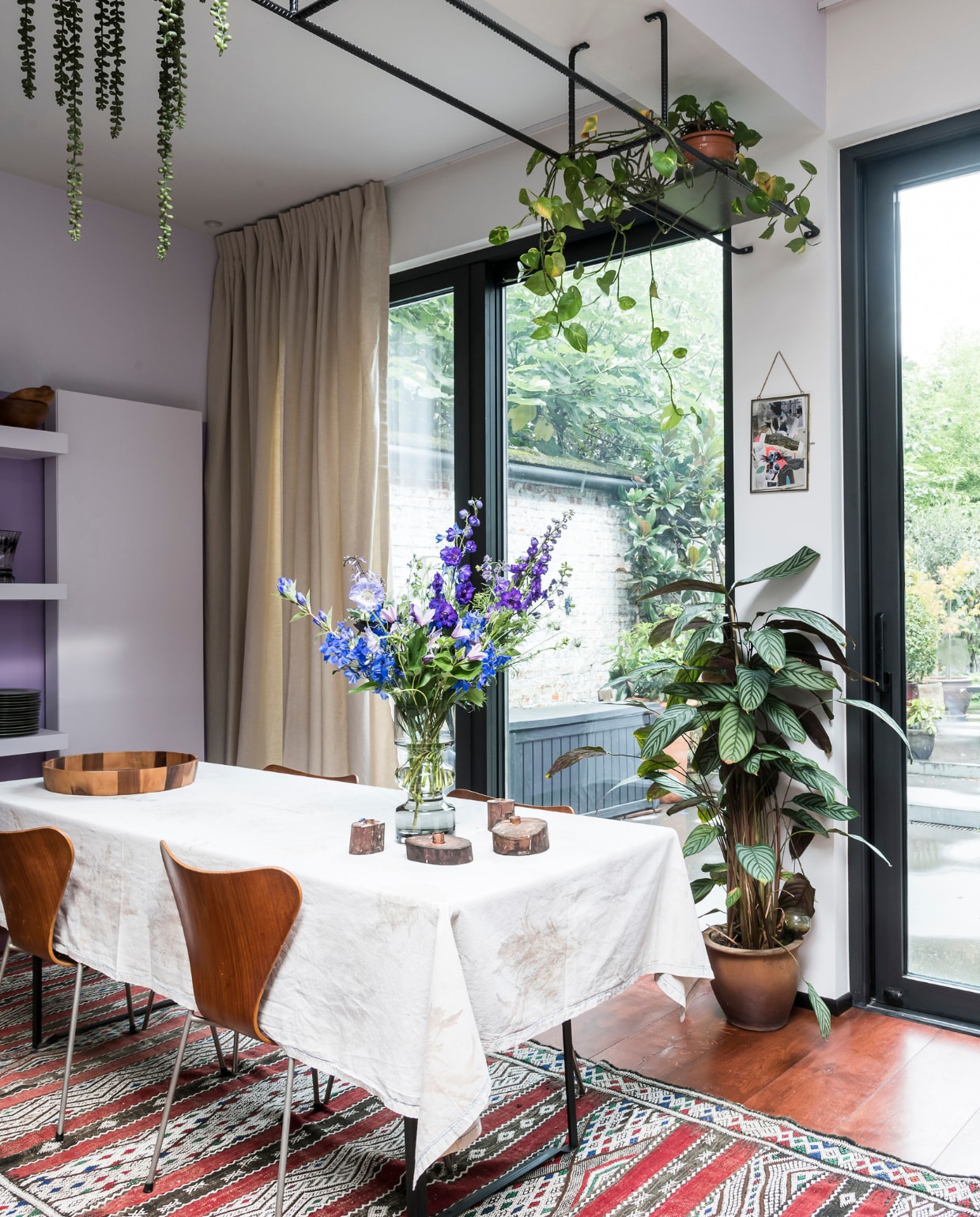 Gordijnen Moodz Designculture. Vlinderstoelen van Arne Jacobsen gekocht bij Cornette de Saint Cyr. Plateau op tafel Dille &amp; Kamille. Tafellaken zelfgemaakt door een vriendin. Kader zelfgemaakt door Caroline. Biertafel, zwart geverfd door Caroline. Vloerkleed The Recollection. De rekken zijn maatwerk. vtwonen 10-2020 | styling Caroline De Cuyper | fotografie Jonah Samyn