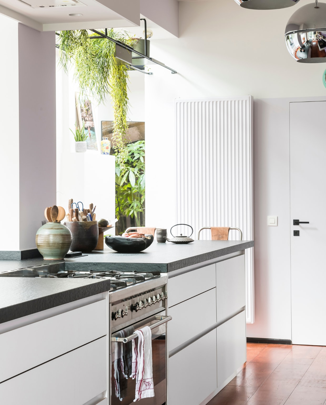 Lila muurverf NCS S 1040 R 50B van SPS, hanglampen vintage. Keuken van keukeninterieur Cascan. De radiator is geschilderd in dezelfde kleur als de muur. Hangrek op maat laten maken. vtwonen 10-2020 | styling Caroline De Cuyper | fotografie Jonah Samyn