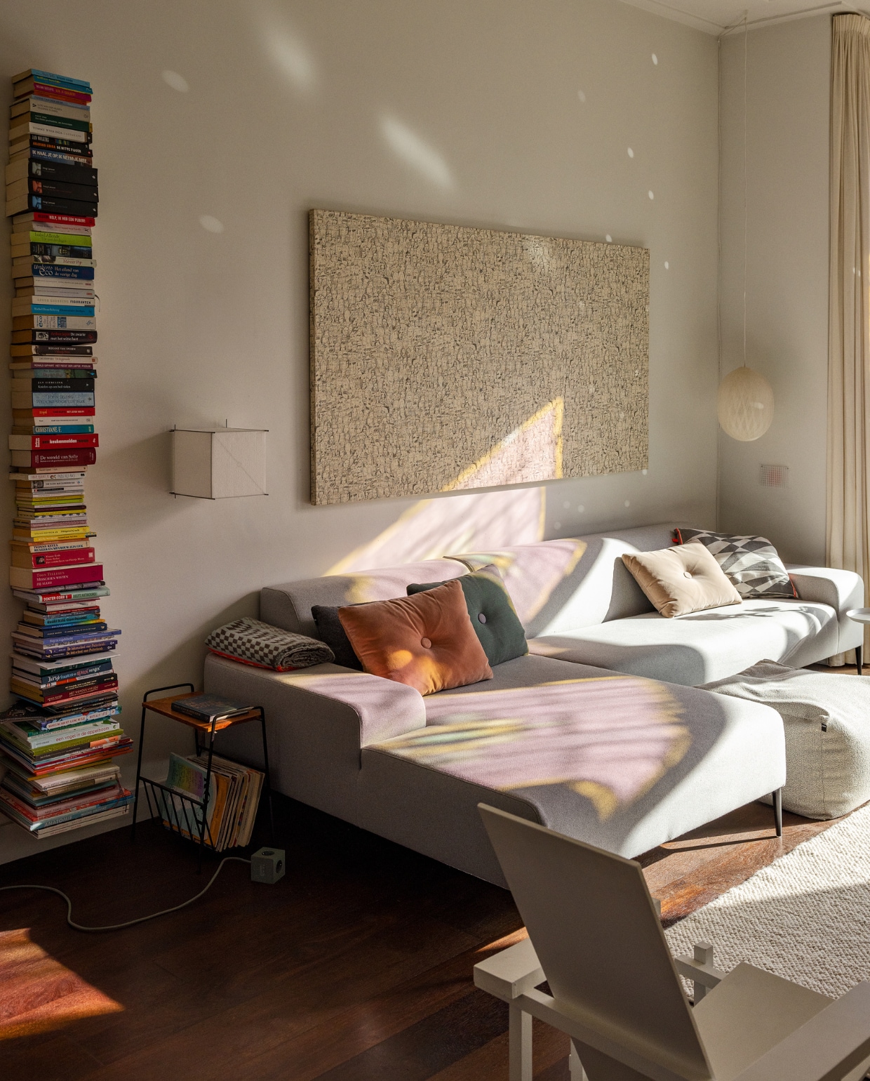 Bank Koozo via Dotshop. Kussens Hay en Studio Mae Engelgeer. Plaid Studio Mae Engelgeer. Poef Hay. Wandlamp Lotek van Hollands Licht, hanglamp Bel + Bo via Petit Depot, vloerkleed Nordic Nest, Rietveld-stoel zelfgemaakt, bijzettafel IJ-Hallen, boekenplank Umbra, lectuurmand tweedehands, kunstwerk zelfgemaakt, gordijnen gemaakt van wit linnen van Kniphal Amsterdam. vtwonen 01-2024 | styling Ilona Jongepier | visagie Djolien de Kreij | fotografie Dana van Leeuwen