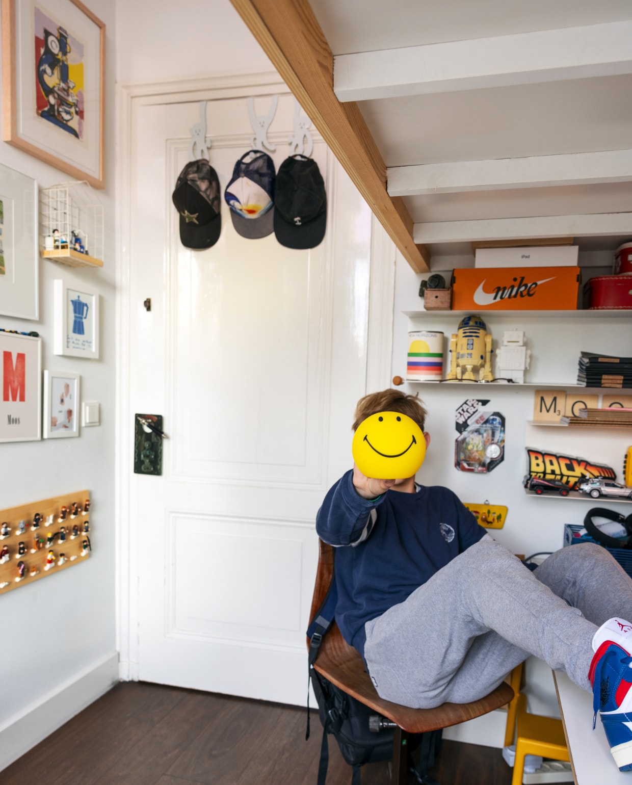 Hoogslaper zelfgemaakt, stoel IJ-Hallen, gele kruk Ikea, Smiley-lamp Mr. Maria, Back to the future-lamp De ToyBoys, apenhaken aan de deur Loods 5. Aan de wand: vosje Marije Tolman, print M van Moos Gwa, plank met legopoppetjes en huisje met playmobil-tandarts zelfgemaakt. Overig onbekend. vtwonen 01-2024 | styling Ilona Jongepier | visagie Djolien de Kreij | fotografie Dana van Leeuwen