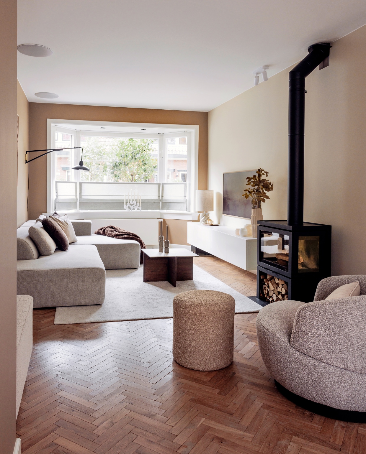 Muurverf achter de bank Bakery Brown van Flexa, achter de tv Crushed Silk van Histor. Kleed en tv-meubel Ikea. Tv The Frame van Samsung. Wandlamp en waxinelichthouder Sissy-Boy. Kussens H&amp;M Home. Vaas en poef Jotex, fauteuil Woolly van BePureHome, plaid Unique Living, kandelaars Como van Westwing Collection. Kachel Vidar Triple Medium van Dik Geurts, vloer Loven Tapis van De Woonzaken. Salontafel zelfgemaakt, Overig onbekend. vtwonen 01-2024 | fotografie Ernie Enkelaar