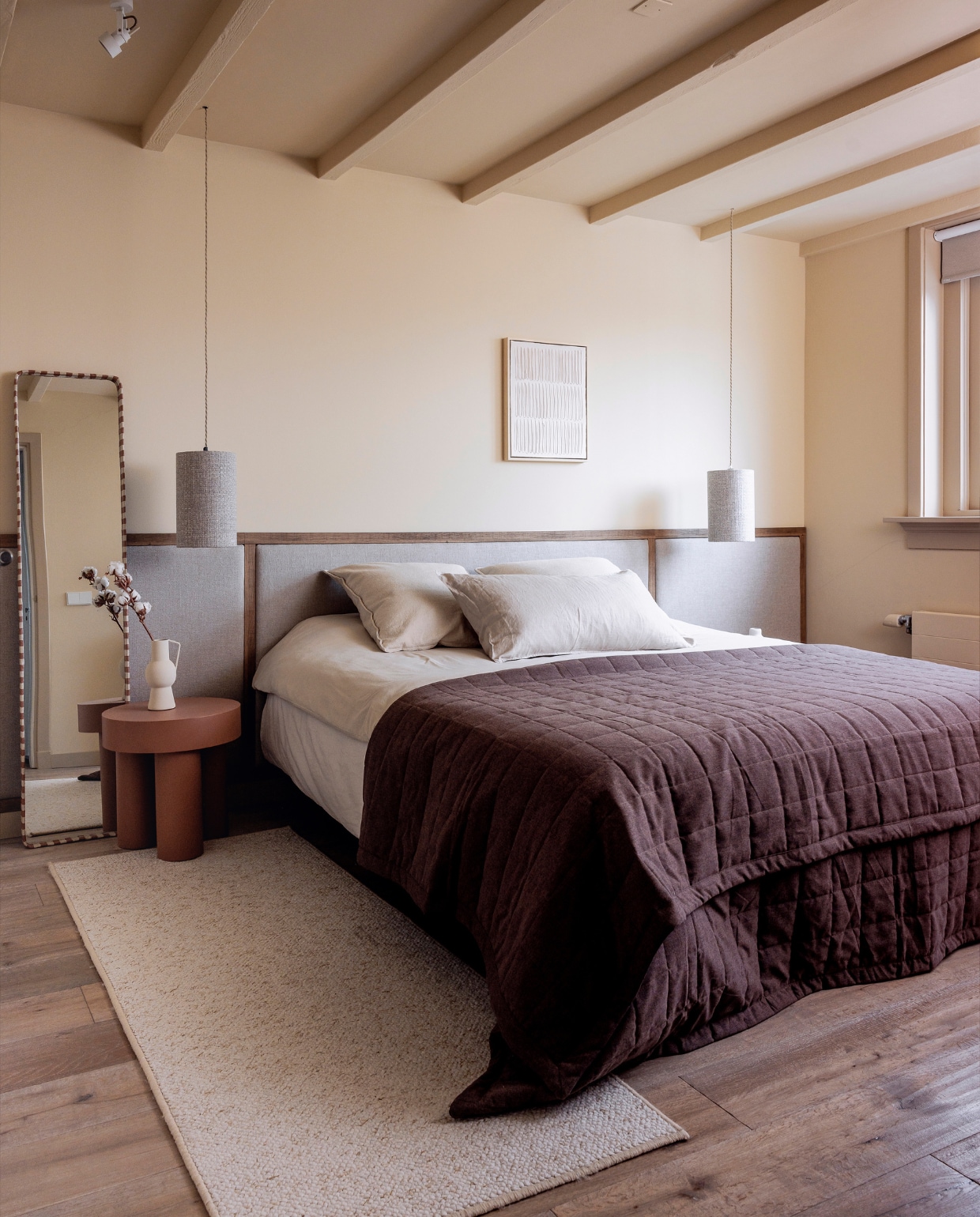 Muurkleur Seriously Sand, kozijnen, plinten en deur in Best Beige van Histor. Lampenkappen BePureHome, vloerkleed Loods 5, sprei Jotex, dekbedovertrek Ambiante. Spiegel, vaas en bijzettafel Kwantum, geschilderd in Prairie Fire van Histor. Wanddecoratie en hoofdbord zelfgemaakt. Houten vloer Zaanbever. Overig onbekend. vtwonen 01-2024 | fotografie Ernie Enkelaar