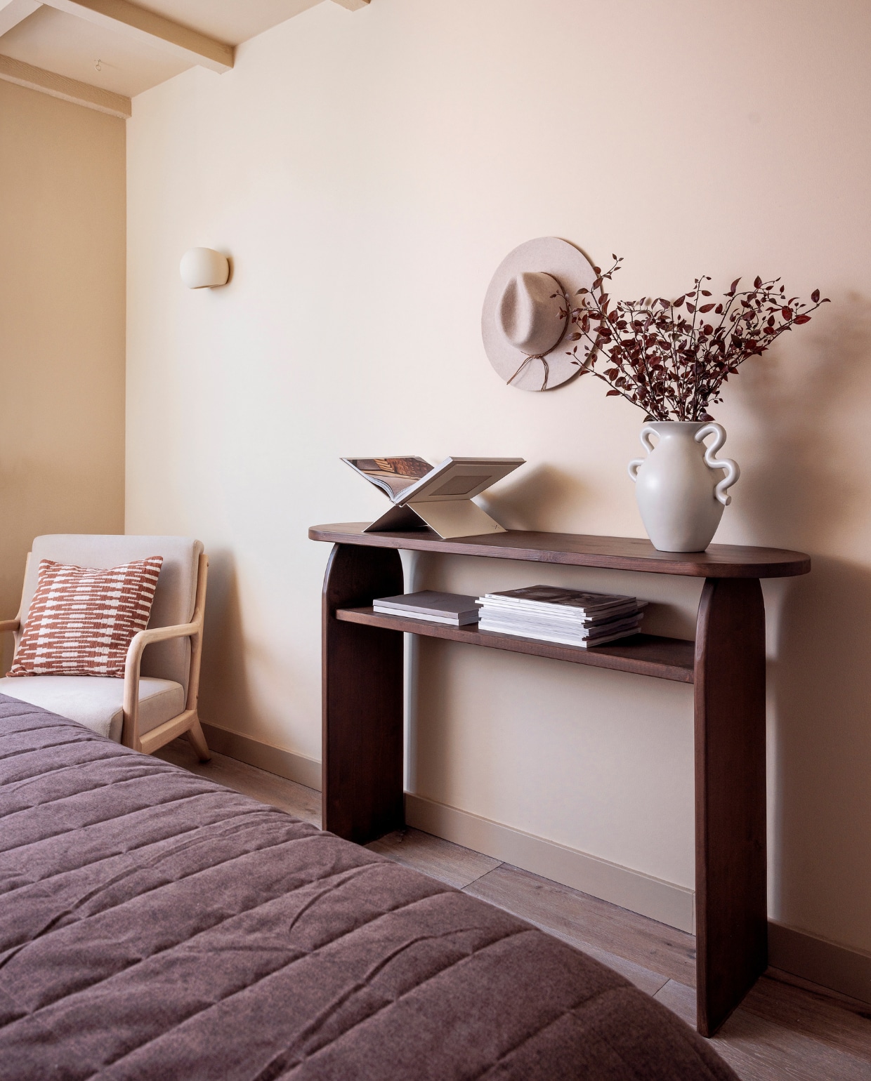 Muurkleur Seriously Sand en plinten in Best Beige van Histor. Fauteuil Mark van Woood, kussen Kwantum, sprei Jotex, wandlamp Mercury van Westwing Collection, hoed Costes, boekenstandaard Animeaux, vaas Ferm Living, sidetable zelfgemaakt. Houten vloer Zaanbever. vtwonen 01-2024 | fotografie Ernie Enkelaar