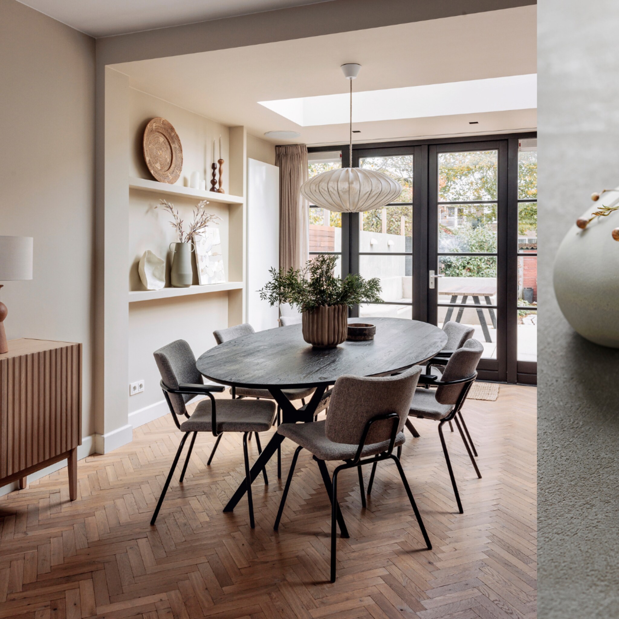 Eetkamer met zes stoelen en een houten visgraatvloer.