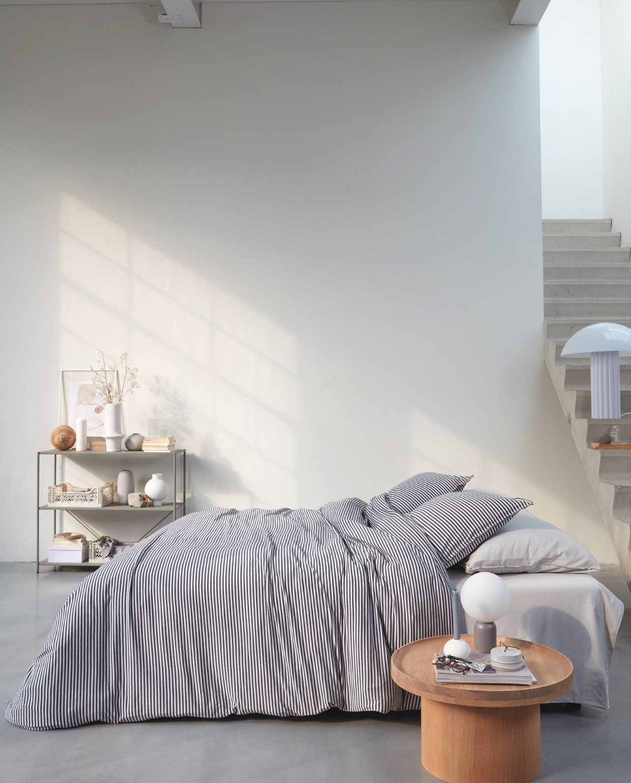 vtwonen collectie (Katoenjersey dekbedovertrek Comfy Stripe in kleur grijs(inclusief kussenslopen)).M.m.v. vtwonen.nl (houten bijzettafel van Bolia, nachtlamp van Bolia), letoile.store (poster in lijst, grijze bolvaas, witte kratten, karaf met glas), loods5.nl (wandkast, witte vazen, grijze langwerpige vaas, witte bolkandelaar, keramieken opberger met deksel). Overig privébezit. vtwonen 04-2021 | productie Tanja Saarberg | styling Daniëlle Verheul | fotografie Richard Smit