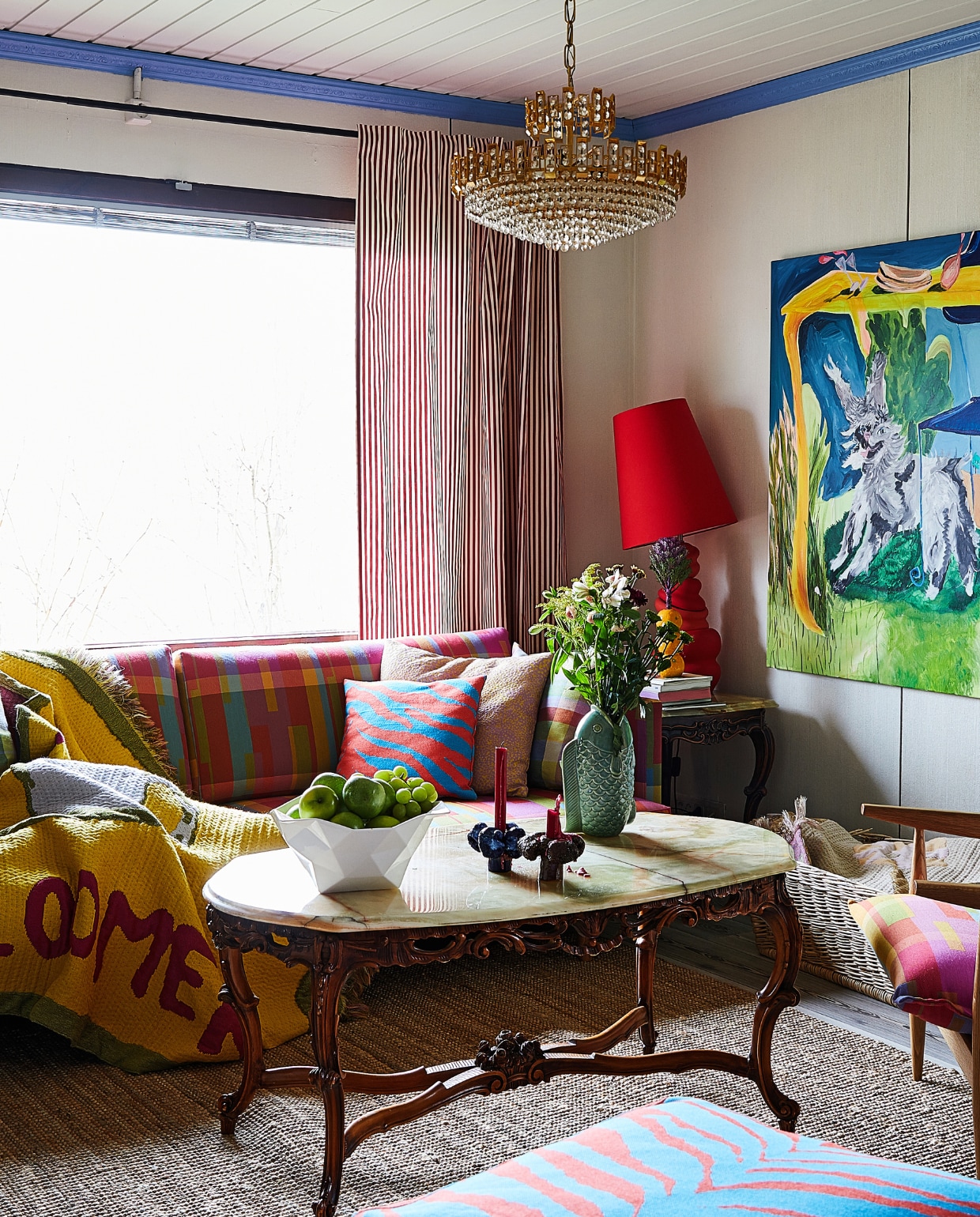 Bank Hakola. Marmeren salontafel en kroonluchter van Laura’s grootmoeder. Kom Muuto, kandelaars Pentik, visvaas H&M Home. Rode schemerlamp, kussens en gordijnen Annala, schilderij Under the Table zelfgemaakt. Overig onbekend. vtwonen special binnenkijken 121-2024 | productie Living Inside | fotografie Krista Keltanen