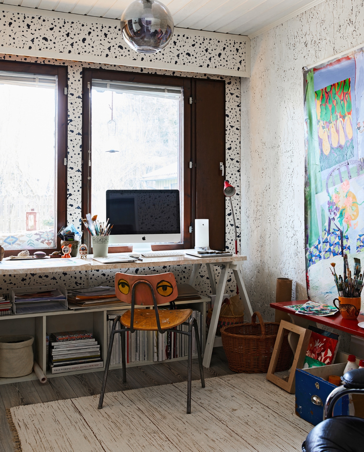 Bureau van schragen Ikea en oud aanrechtblad, oude schoolstoel zelf beschilderd. Rode bank en lamp kringloop. Overig onbekend. vtwonen special binnenkijken 121-2024 | productie Living Inside | fotografie Krista Keltanen