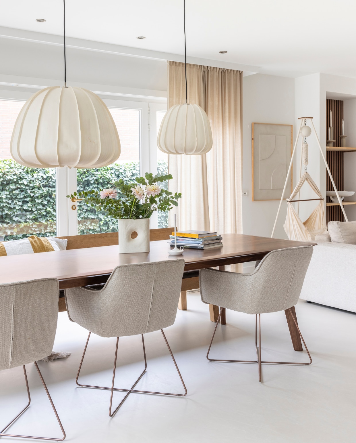 Gietvloer Arturo, muurverf Ral 9016, eettafel De Machinekamer, stoelen Jesper Home, eetkamerbank Pilat&amp;Pilat, hanglampen Ay Illuminate, vaas By-Boo, kandelaar Wick, gordijnen Karwei, babyhangmat Moonboon, wanddecoratie Hout van Toen, bank Room108. Overig onbekend. vtwonen 03-2024 | fotografie Margriet Hoekstra