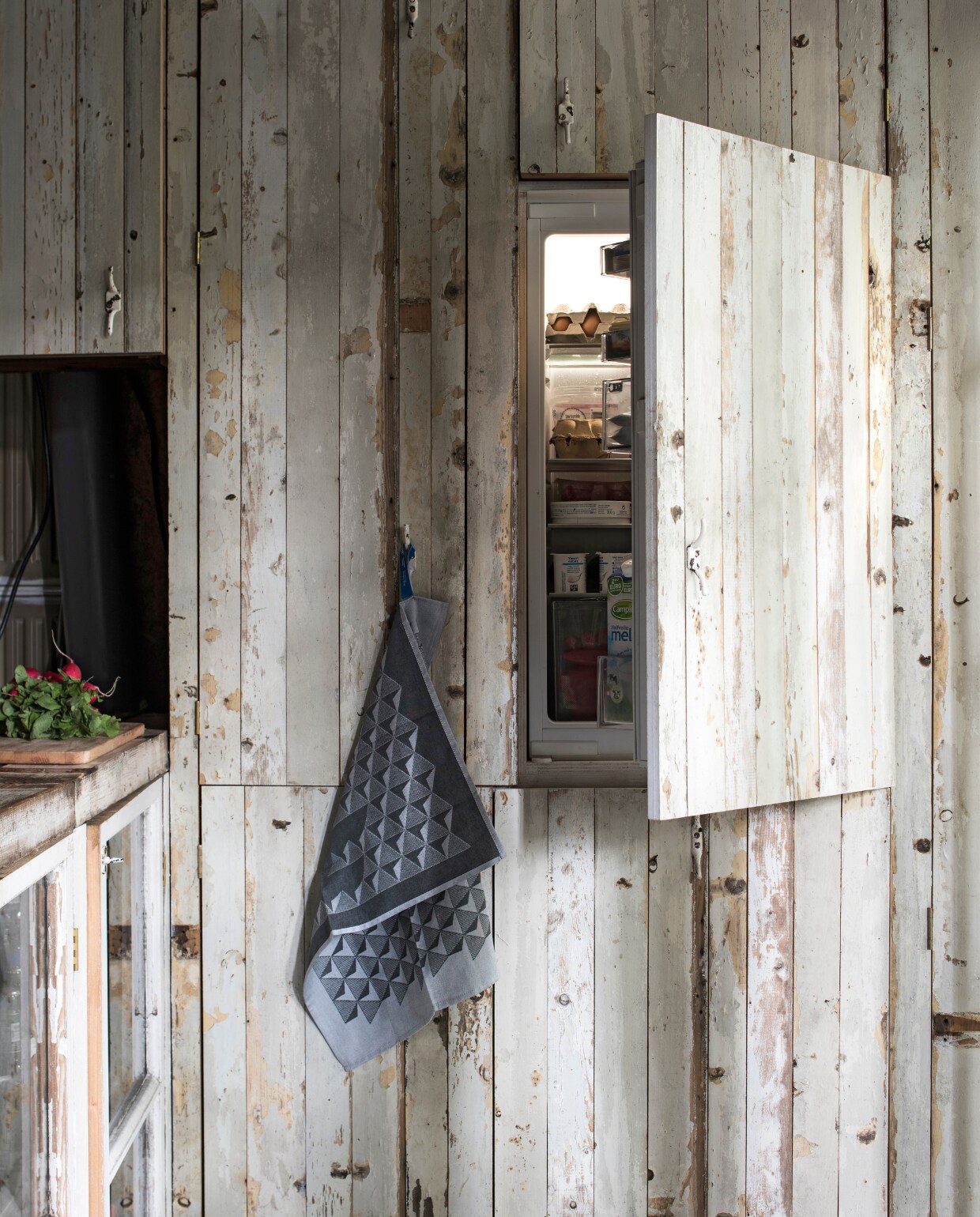 De koelkast en vaatwasser zitten verstopt in een kastenwand. Theedoek van Richard van Os van HUH designer goods. vtwonen 03-2017 | styling Inge van Lieshout | fotografie Louis Lemaire/Insidehomepage