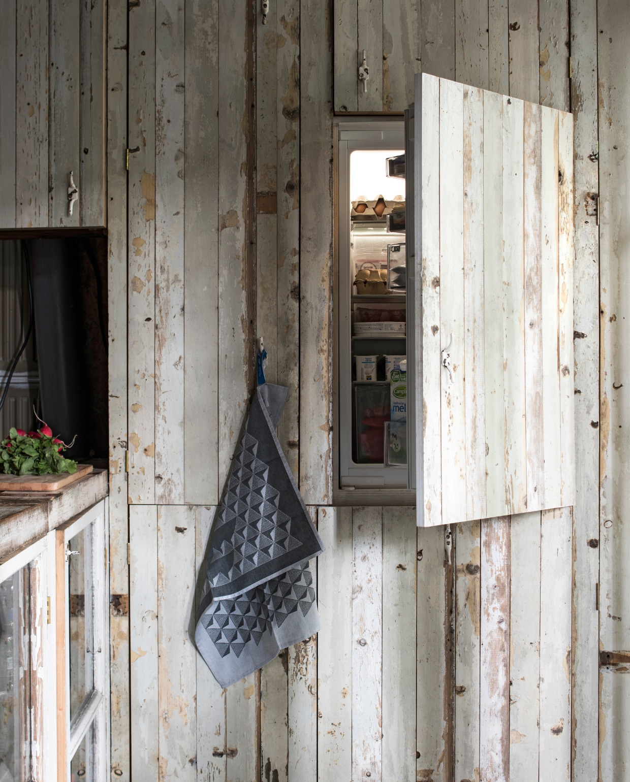 De koelkast en vaatwasser zitten verstopt in een kastenwand. Theedoek van Richard van Os van HUH designer goods. vtwonen 03-2017 | styling Inge van Lieshout | fotografie Louis Lemaire/Insidehomepage