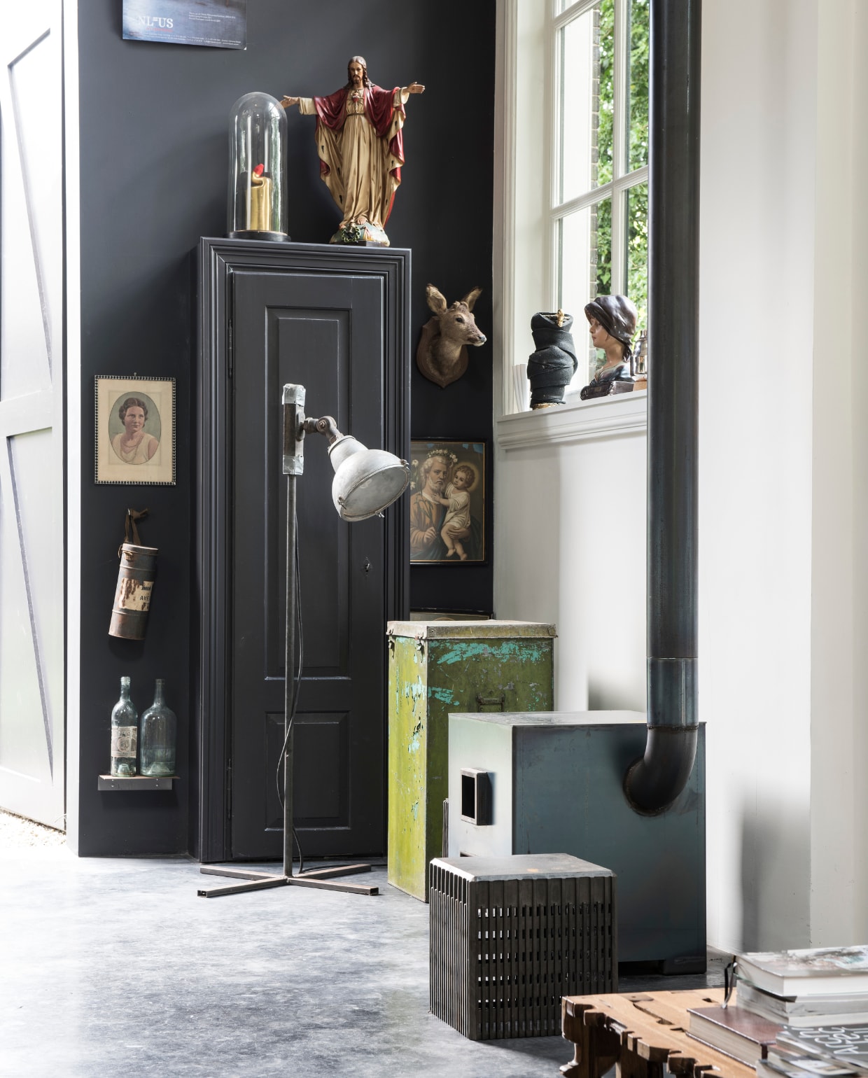 Met mooi weer gaan de originele koetshuisdeuren open. Links staan twee hoge objecten, geïnspireerd op de Twin Towers in New York. Op deze wand krijgen kunst, foto’s en souvenirs een podium. Linksboven staat een rioleringsbuis uit Tanzania als een pronkstuk onder een stolp. Er staan religieuze beelden gevonden in Frankrijk en er hangt ook een bovenkant van een olievat, dat Rolf en Yffi vonden in Senegal. Rolf: ‘De vaten worden daar op allerlei manieren hergebruikt en wij vonden het een mooi souvenir.’ Er hangt ook een te koop bord van hun vorige woning in Rotterdam. Rolf en Yffi noemden de woning De Zwarte Parel. vtwonen 03-2017 | styling Inge van Lieshout | fotografie Louis Lemaire/Insidehomepage