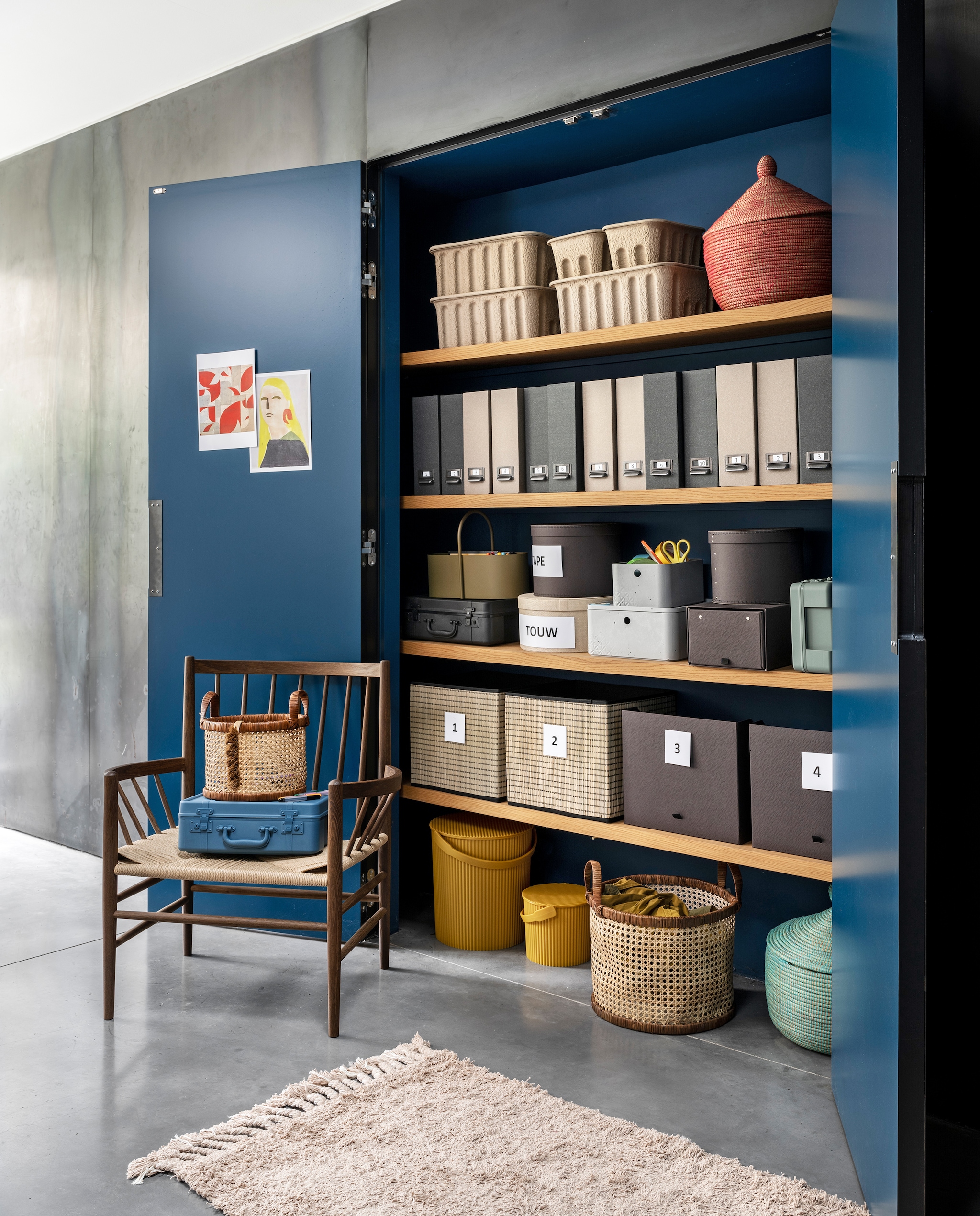 Gele emmers van Hachiman, klein € 16,25, groot € 25,-, olijfkleurige toolbox van Ferm Living € 65,-, betongrijze doos van Curver, medium € 16,15, small € 12,65, deksel medium € 8,90, blauwe en zwarte kunststof koffers van Hachiman, small € 29,95, medium 44,95 (vtwonen.nl). Ronde manden van webbing met leren rand vanaf € 29,99 (hm.com). Naturel ronde doos uit set van 3 € 14,95, donkergrijze ronde dozen, set van 2 € 9,99, uitschuifbare doos voor schoenen € 4,99, lectuurbak Tjog in naturel en donkergrijs, set van 2 € 3,99, rieten inklapbare dozen onderin € 7,99, rechts daarvan doos Anilinare € 5,99 (ikea.nl). Kartonnen dozen van Ferm Living op bovenste plank vanaf € 25,-, loper van Ferm Living € 119,- (misterdesign.nl). Rood-blauwe mand met deksel € 24,95 (basketsbeads- basics.nl). Stoel van FDB Møbler in smoked oak, 76,5x63x85 cm (bxdxh) € 1149,- (eijerkamp.nl). Soortgelijke muurverf T04030, prijs op aanvraag (flexa.nl). vtwonen 04-2021 | styling Marianne Luning | fotografie Stan Koolen