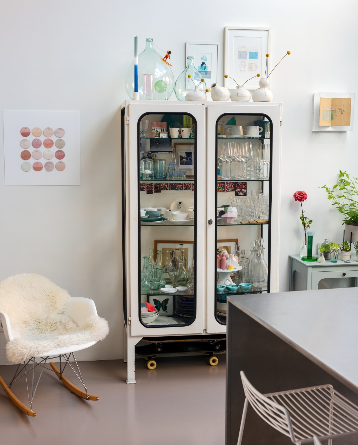Schommelstoel Eames, vitrinekasten Marktplaats, barkruk Hay, lijsten Ikea. Kunstwerken aan de muur: keramiekstalen Form Keramiek, Een Allegaartje en Woordzaken. Kandelaar Studio Berger, kaars Mo Man Tai, vazen Studio About. In de vitrine: vazen Foekje Fleur, Hella Duijs en Räder, beschilderde tegels Lemonwise, paardenbloemlamp Studio Drift, kop en schotel met pentekening Polspotten, auto Floris Hovers, kandelaar Mona van Suzanne Stevense, kop en schotel Maarten Baas, pastisglazen en kristallen glazen van vide greniers in Frankrijk. Keramiek, vazen en karaffen van diverse tweedehands markten. vtwonen 01-2024 | styling Ilona Jongepier | fotografie Dana van Leeuwen