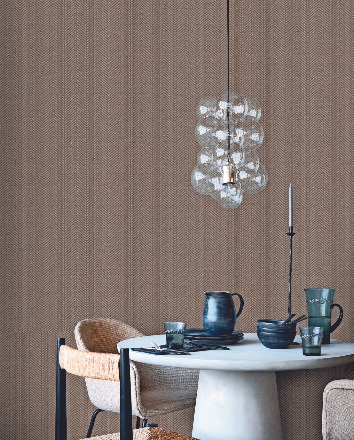 Vliesbehang Herringbone Soil/Gold, 53 cm x 10 m (bxl), per rol € 34,99.M.m.v. vtwonen.nl/shop (hanglamp DIY van House Doctor), basiclabel.nl (eettafel Damon van Woood), loods5.nl (gestoffeerde eetkamerstoelen), zarahome.com (zwarte eetkamerstoel met rotan, serviesgoed, bestek), sissy-boy.com (waterglazen, karaf, kandelaar), letoile.store (servet). vtwonen 02-2024 | productie Tanja Saarberg | styling Sanne Ketelaar, Danielle Verheul | fotografie Sjoerd Eickmans, Peggy Janssen