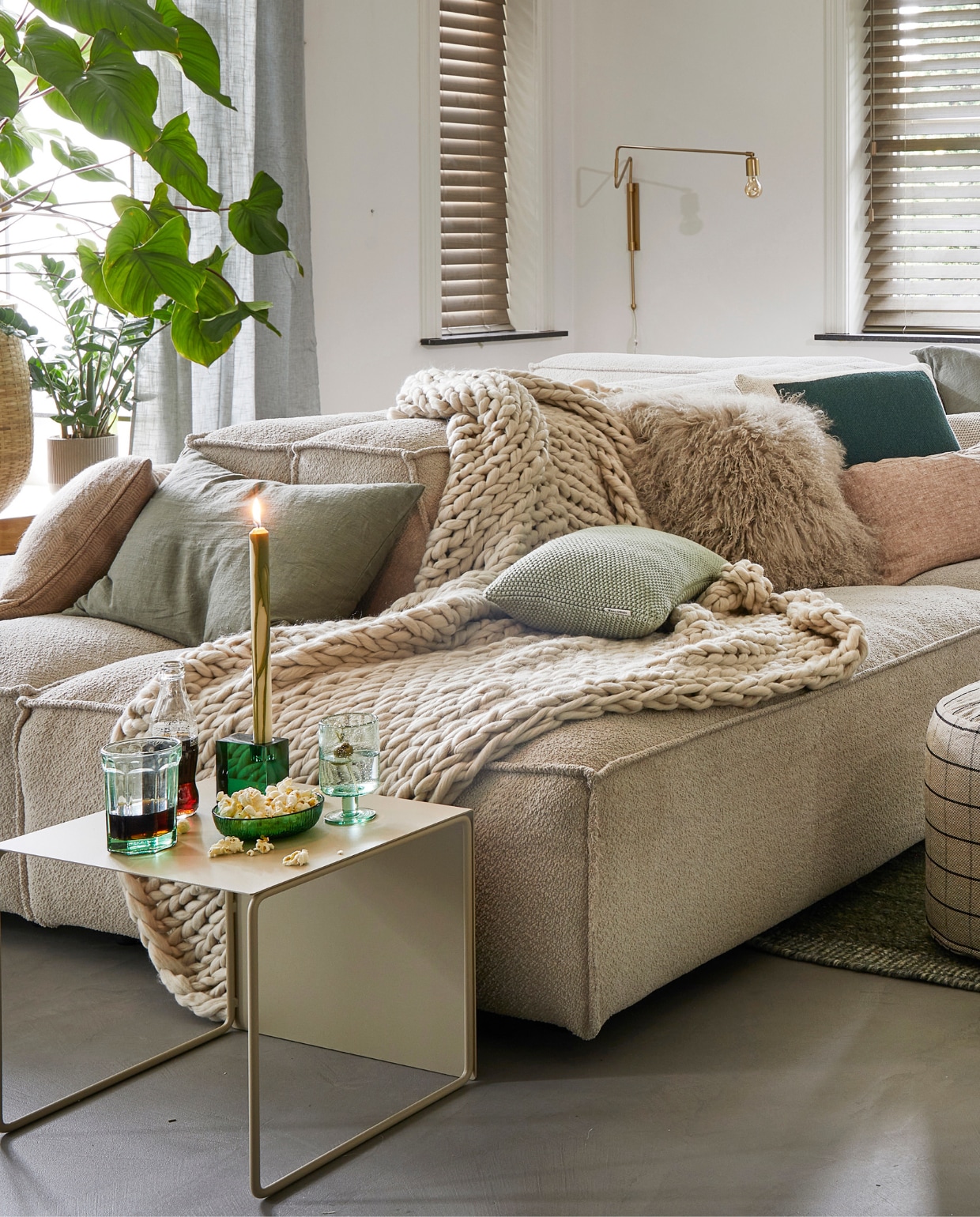 Ecru elementenbank Square van Easy Sofa, per module vanaf € 605,- (hoekbankxxl.nl). Groen geweven vloerkleed Versanti van Linie Design, 240x170 cm € 440,- (vtwonen.nl). Ecru metalen bijzettafel Cluster van Ferm Living, set van 3 € 380,-, grijze geruite poef Grid van Oyoy, 40x38 cm (Øxh) € 104,55, groene kristalglazen kandelaar Parker, 8x3x8 cm € 24,65 (wonenmetlef.nl). Crèmekleurige gebreide plaid, 152x127 cm € 149,- (noirhome.nl). Kussens van links naar rechts: lichtbruin kussen met visgraatmotief Kata van Oyoy, 40x60 cm € 57,80 (wonenmetlef.nl), linnen kussen Olive, 40x60 cm € 59,- (bymolle.com), kussen Nordic Knit van Marc O’Polo, 30x60 cm € 39,99 (vtwonen.nl), schapenvachtkussen, 40x40 cm € 69,- (noirhome.nl), groen gebreid kussen Solid van Malagoon, 50x50 cm € 49,99 (vtwonen.nl), linnen kussen Blush, 35x50 cm € 49,-, gerecycled gebreid denim kussen Sand, 40x60 cm € 79,-, linnen kussen Olive, 60x60 cm € 69,-, linnen kussen Cinnamon, 40x60 cm € 59,- (bymolle.com). Donkergroene merinowollen deken van McNutt, 200x145 cm € 100,-, groen glas van Serax, medium € 9,50, groene glazen popcornschaaltjes Emeralds, 12,5 cm (Ø), per stuk € 12,10, groen aardewerken chipsschaaltje Miscellaneous € 7,- (vanmanenaantafel.nl). Gerecycled wijnglas Oli van Ferm Living € 25,-, gerecyclede glazen karaf Oli Jug van Ferm Living € 39,-, groene kaars Dryp van Ferm Living, per 2 € 11,-, metalen plantenbak op poten Two Tier van Ferm Living, 25x75x80 cm € 299,-, fotolijsten aan rechter wand, vanaf € 35,- (byjensen.nl). Plant Philodendron, groot € 149,95, bamboe mand € 200,-, op side table plant Philodendron € 22,50, groene metalen pot € 35,-, plant rechts Monstera € 28,95, plant voor Asparagus € 44,95, bamboe mand € 89,- (stadstuindebloemenpoort.nl). Messing wandlamp Swing van House Doctor, 65x35 cm € 199,-, mosgroene keramieken vaas Eminent Circles, medium € 49,99, keramieken tafellamp Stoneware met lampenkap van HKliving € 209,- (vtwonen.nl). Terracotta bloempot Rosa, 12 cm (Ø ) € 9,50 (bymolle.com). Lichtbruin aardewerken suikerschaaltje Hagi van Oyoy (wonenmetlef.nl). Overig privébezit. vtwonen 02-2023 | styling Femke Pastijn | fotografie Peggy Janssen