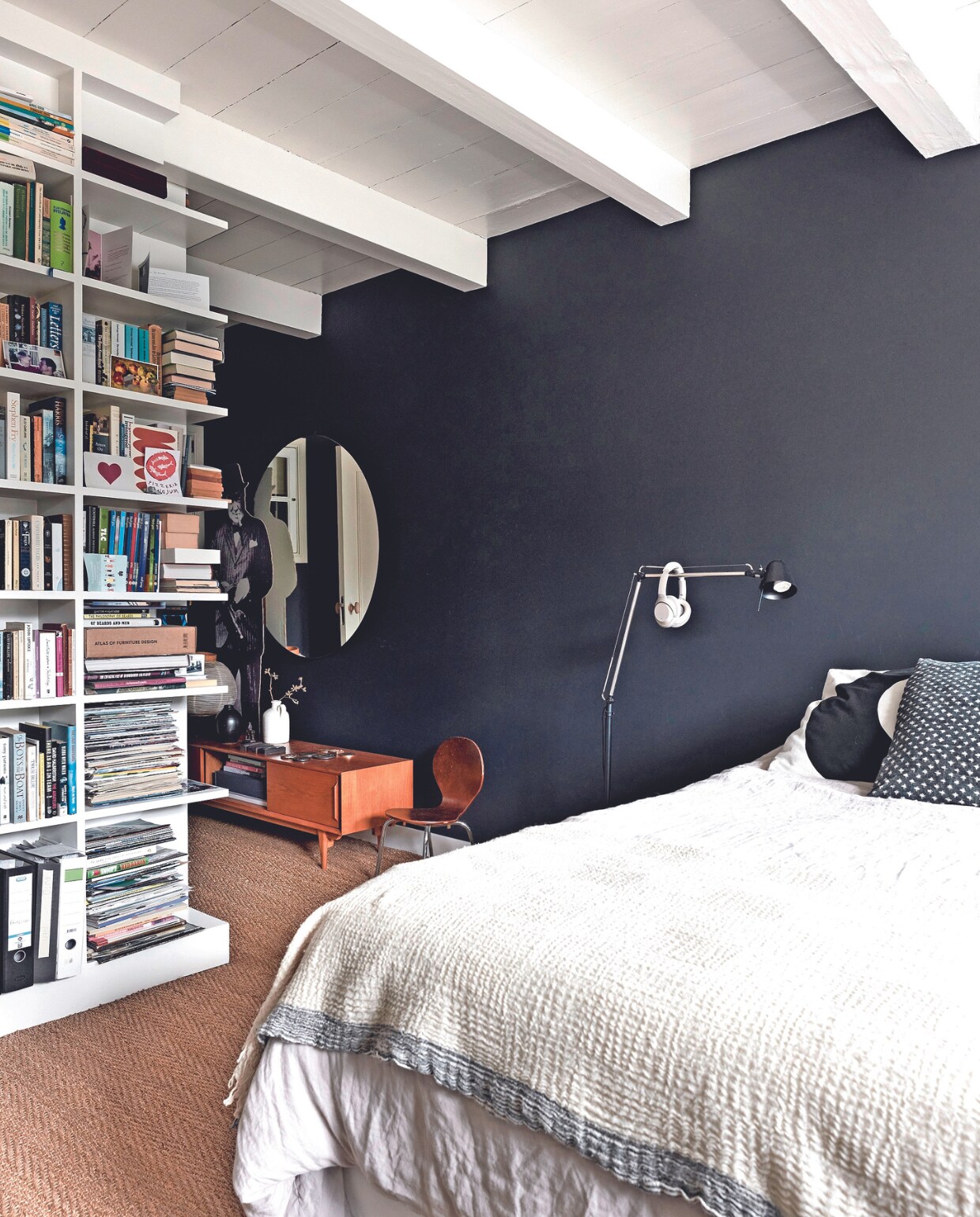 vtwonen 02-2024 BK3 - Boekenkast op maat gemaakt door Johan Snodijk, ontwerp Heleen. In de kast diverse kaarten en familiefoto’s. Stalamp, sprei, bollamp en spiegel Ikea. Headphones Sony. Kussen grote cirkel en witte vaas vtwonen. Zwarte vaas Tessi Schenk. Kussen met dots en kartonnen Churchill bij spiegel cadeau. Vintage dressoir Maisons du Monde, zeegras vloerbedekking Cunera. Muurverf Royal Blue van Flexa. Overig onbekend. vtwonen 02-2024 | fotografie Alexander van Berge